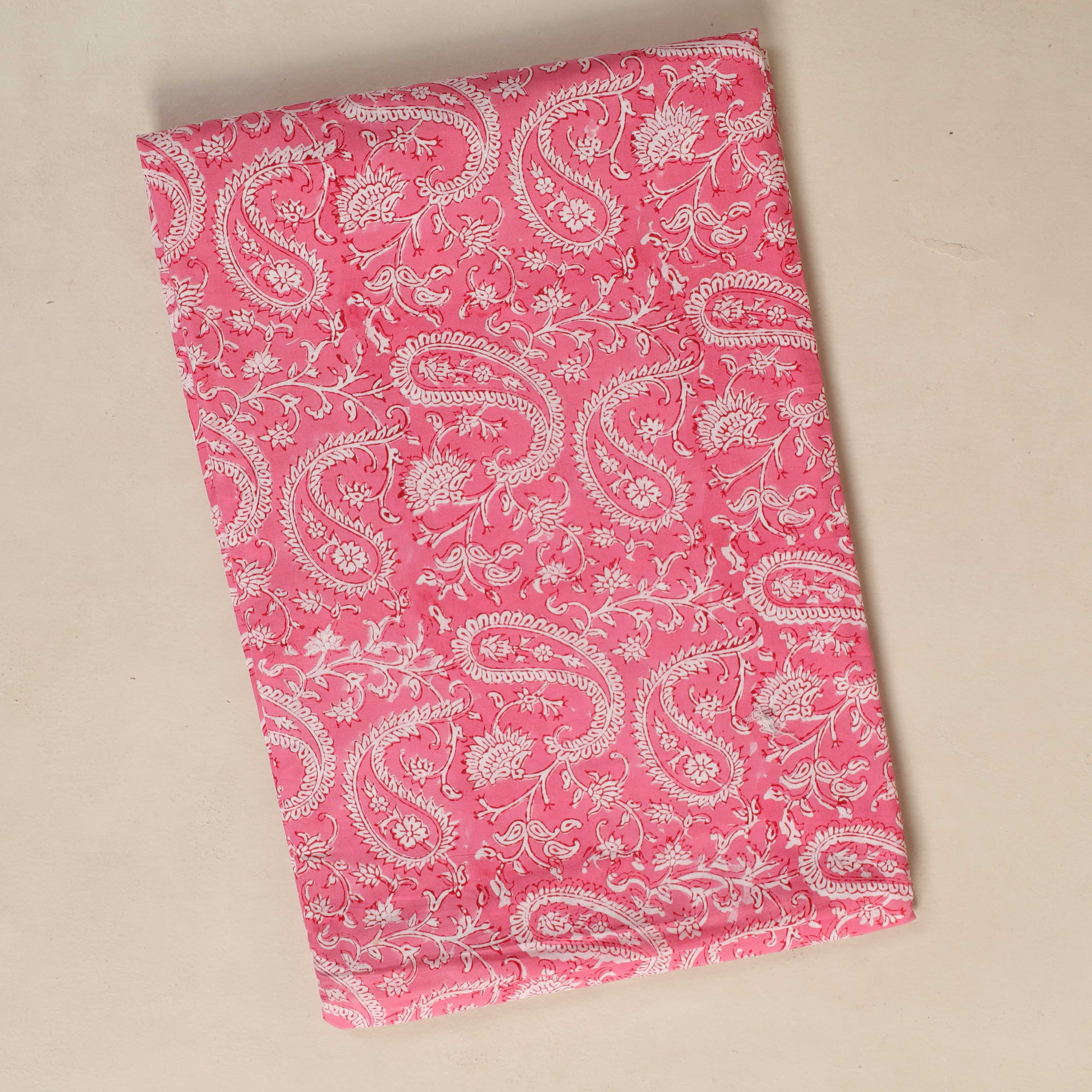 Pink fabric with white paisley pattern on a beige background