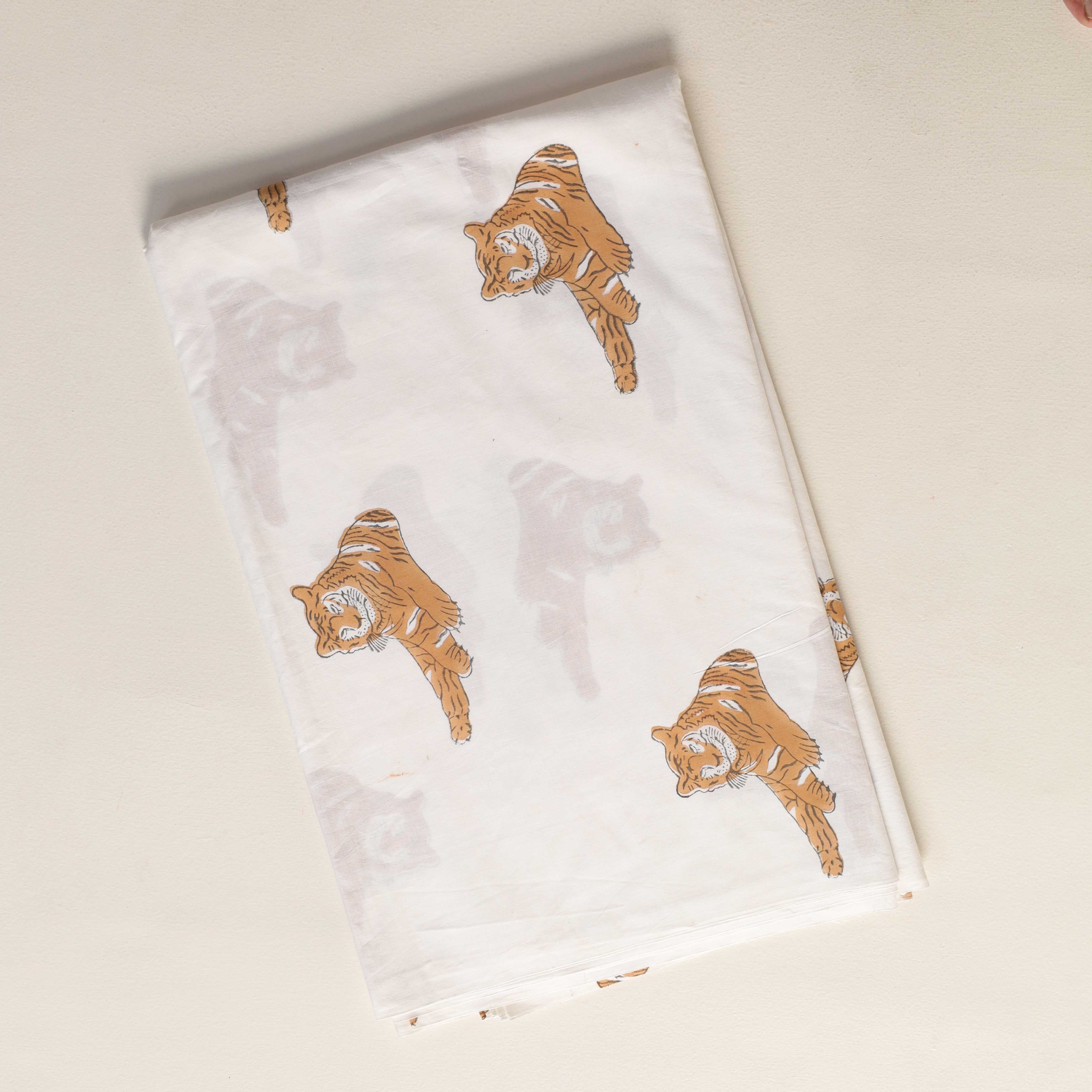 Folded white towel with gold tiger prints on a beige background