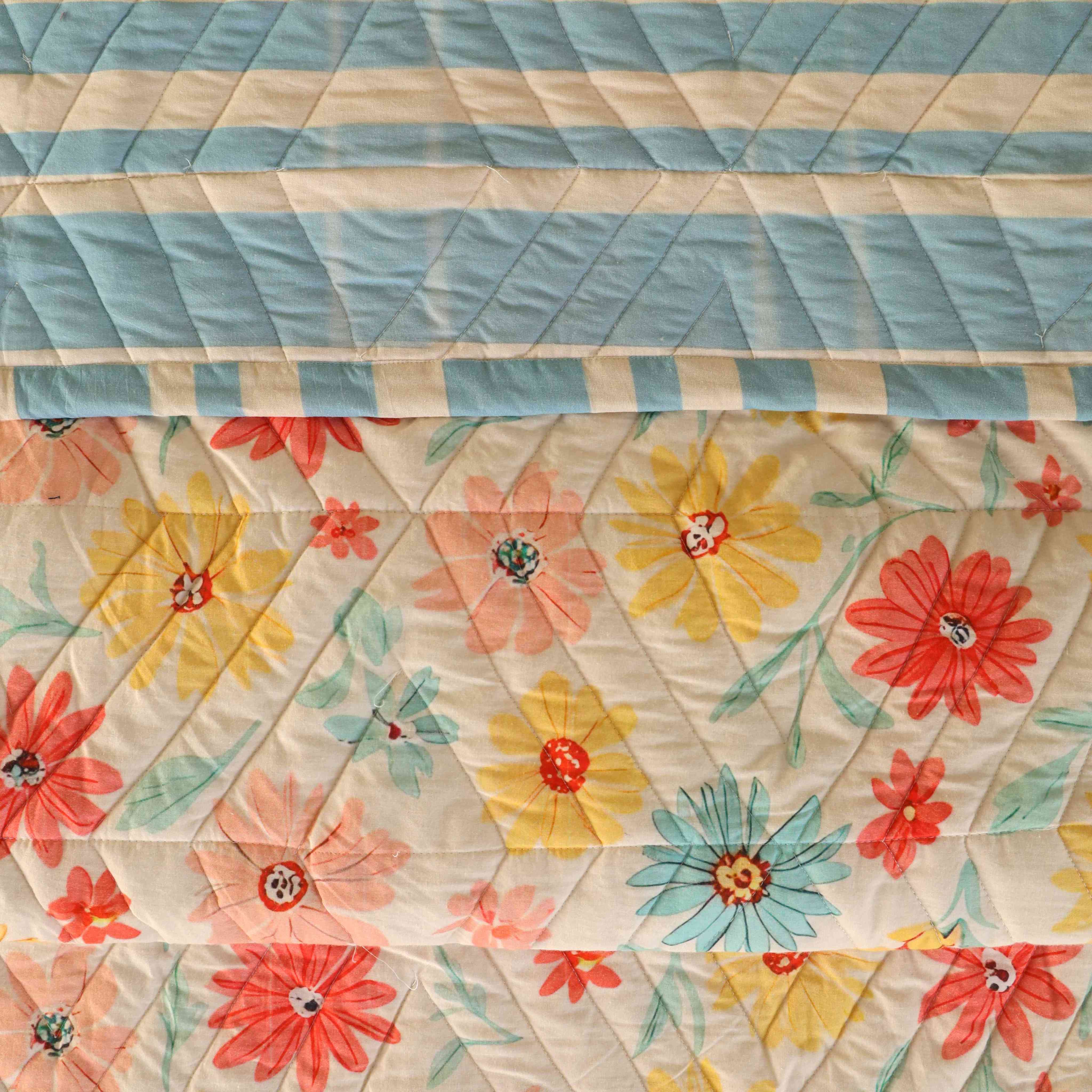 The reversible side of a cotton quilt featuring a modern blue and white striped pattern.