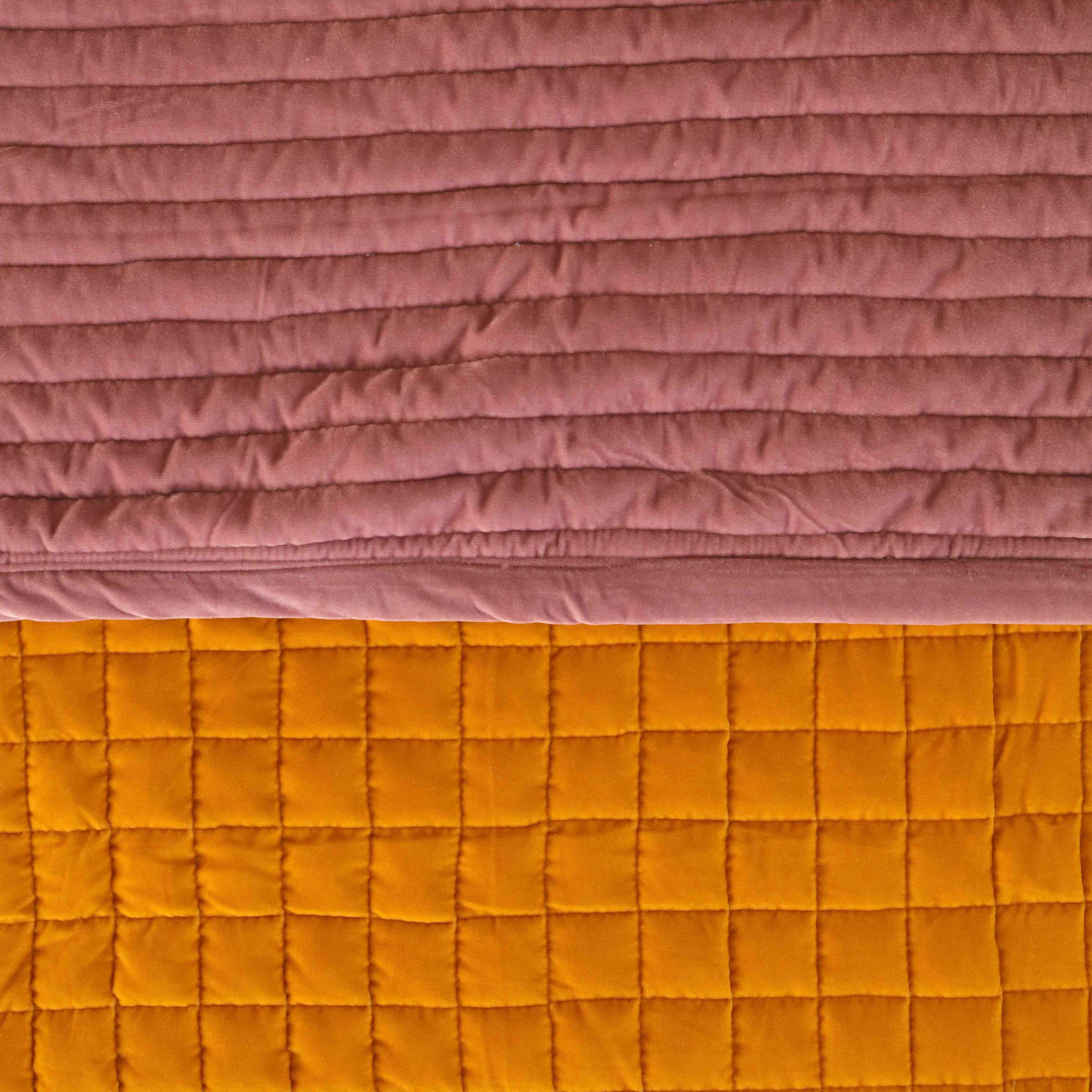Close-up detail of the horizontal quilting on soft reversible mustard yellow and dusty pink velvet fabric.