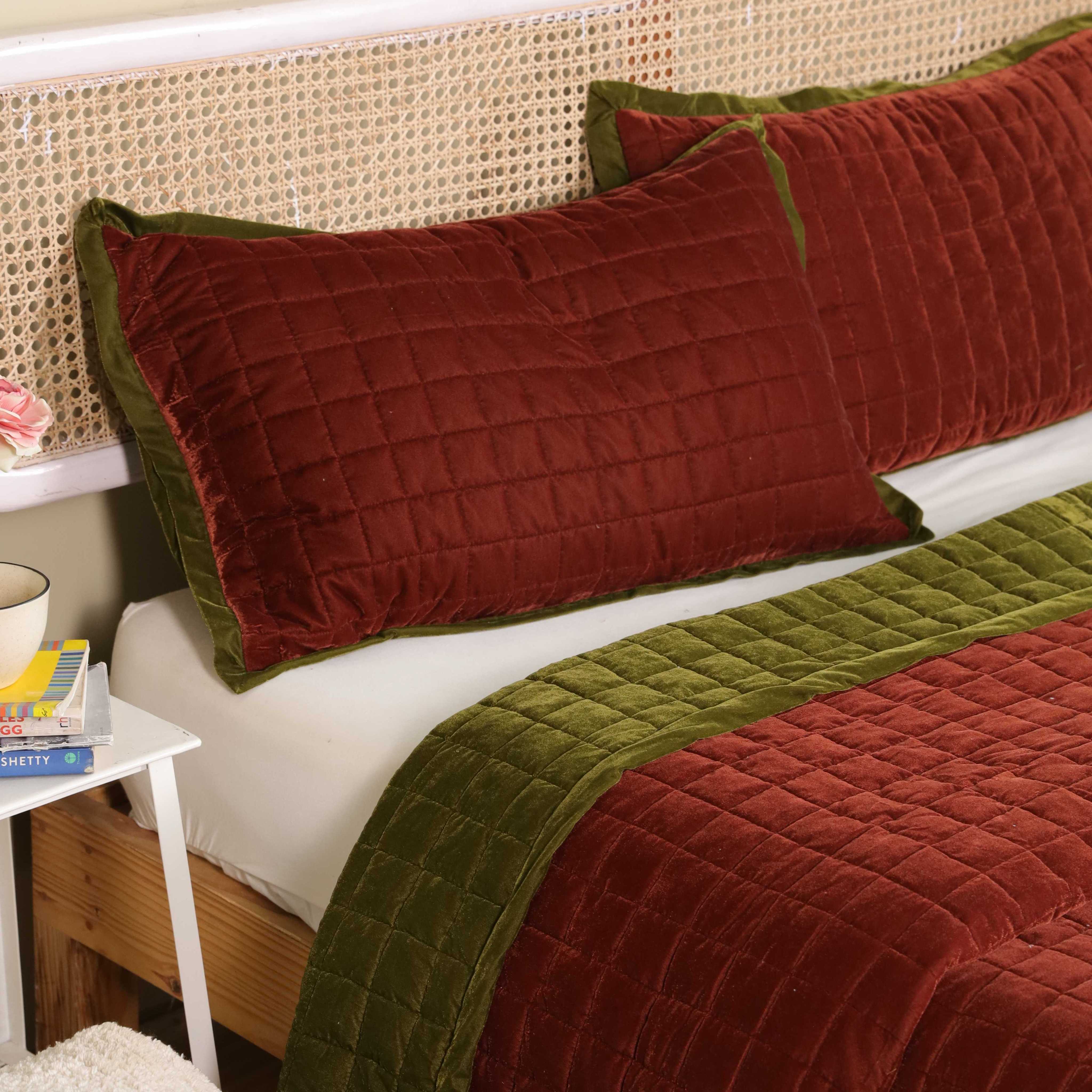 Close-up of plush velvet fabric with a modern box quilted pattern in brick red.