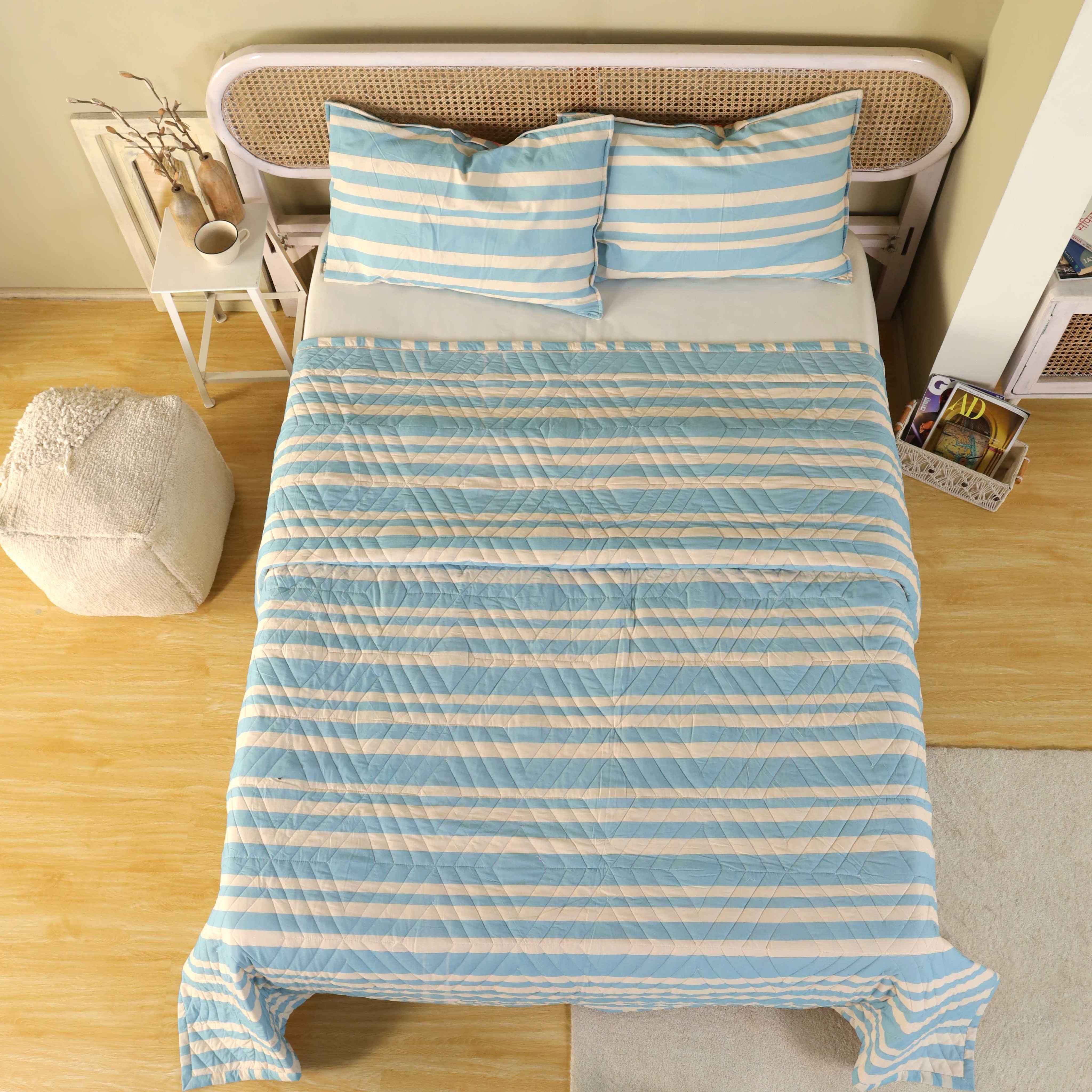 Modern bedroom interior featuring a blue striped velvet comforter and minimalist decor.