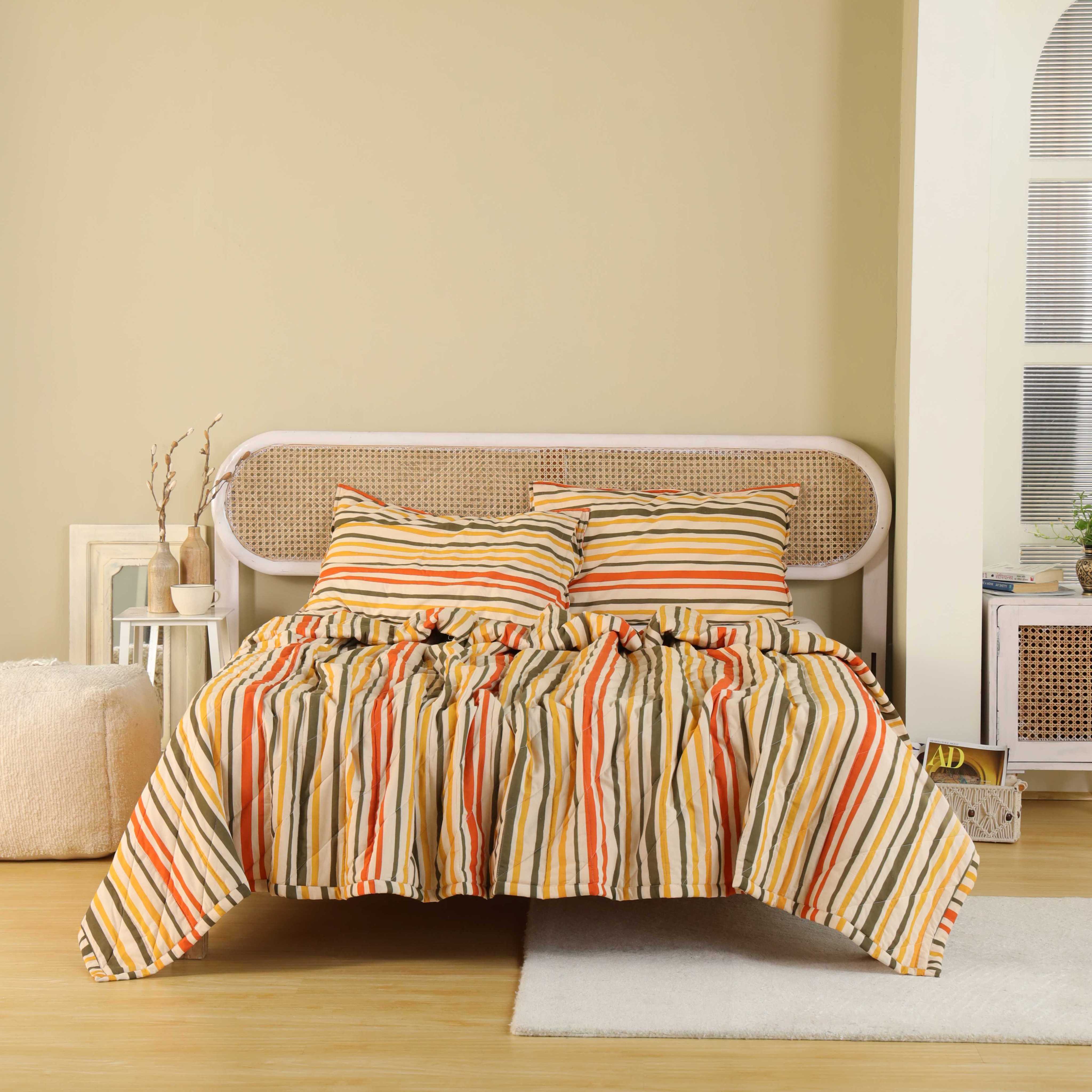 Close-up of the orange, green, and gold vertical stripes and diamond quilting on a cotton quilt.