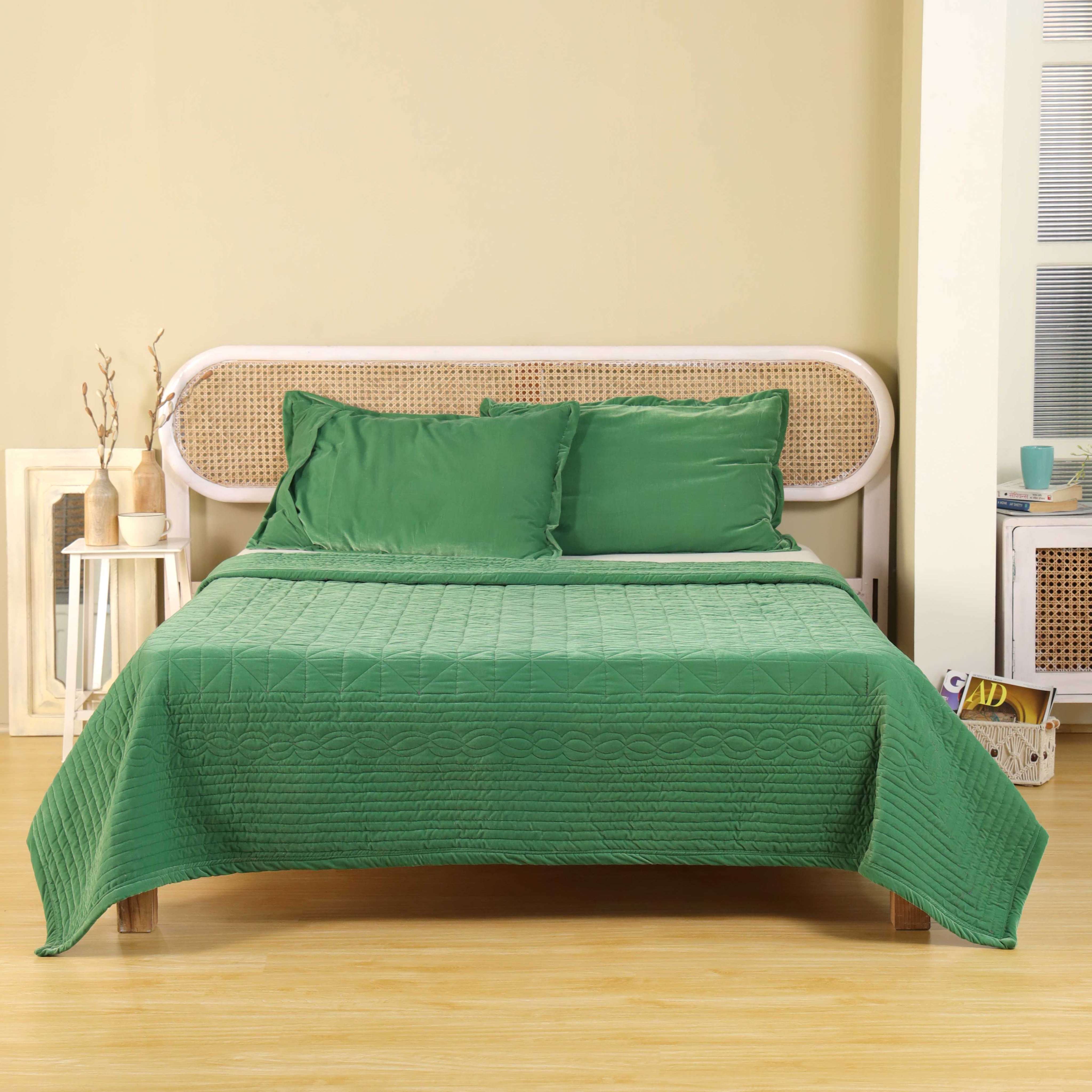 Emerald green satin duvet cover with intricate geometric and scroll quilting on a modern bed.