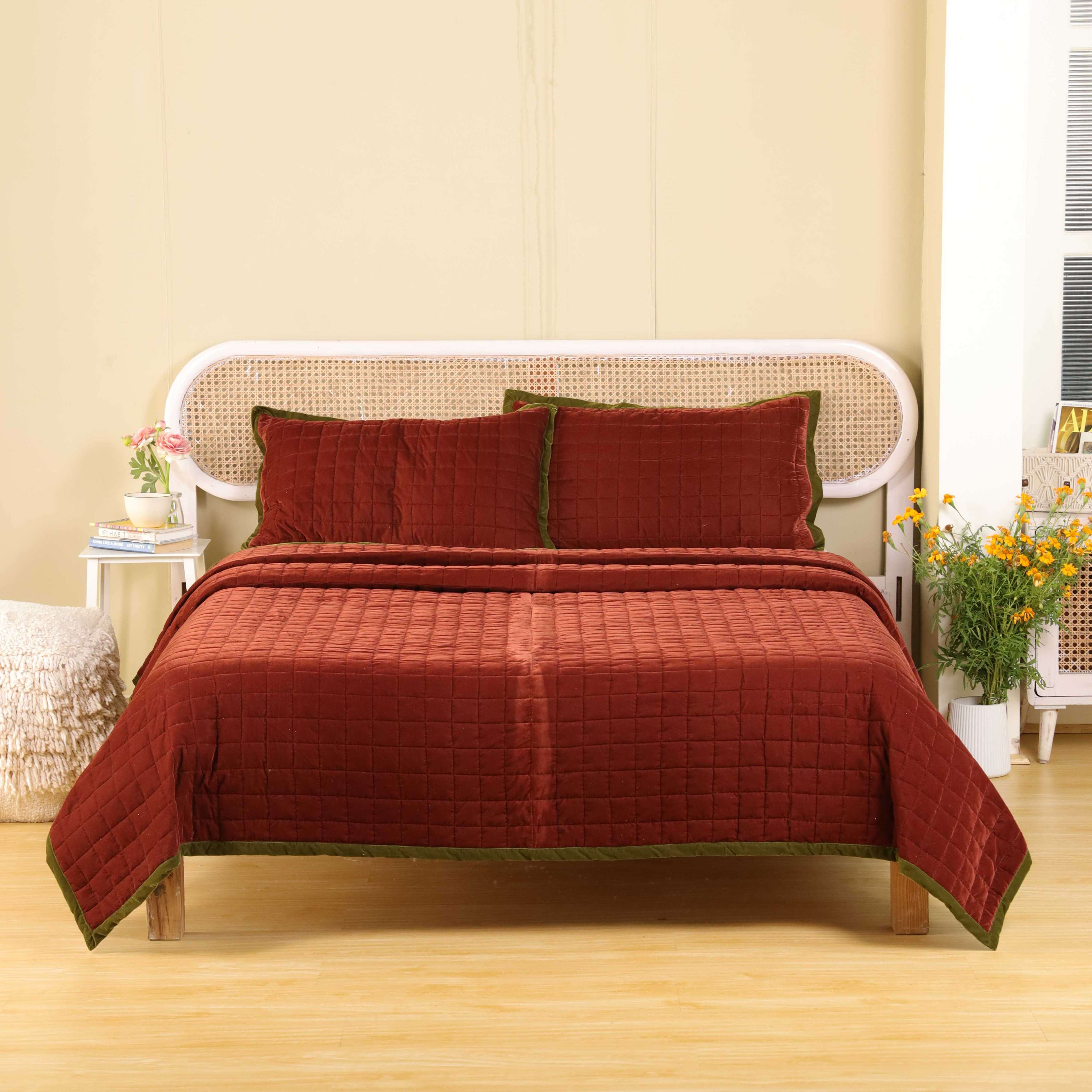 Faded maroon velvet duvet cover with olive green trim on a modern cane headboard bed.