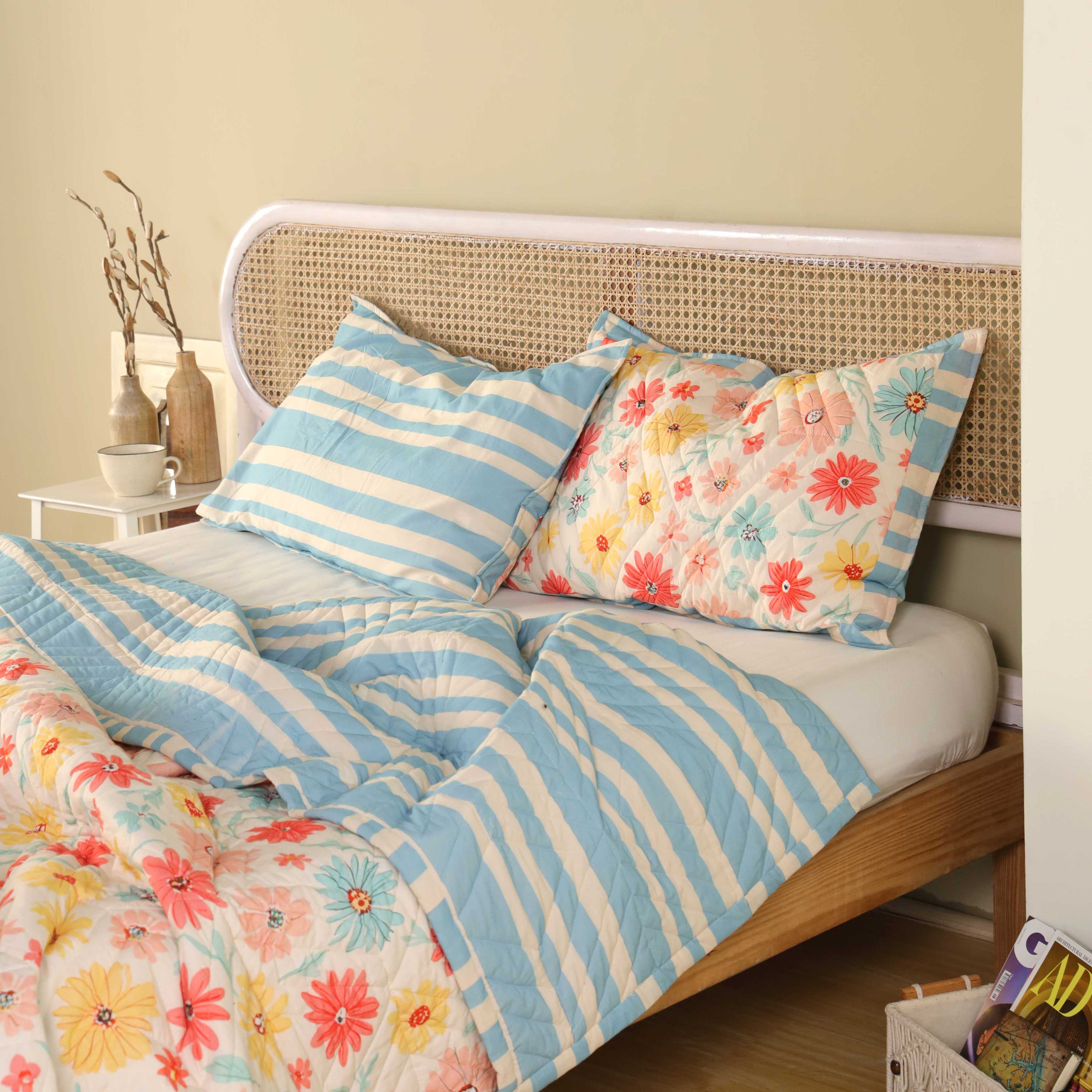 A neatly folded multi-color floral cotton quilt showing both the print and striped sides.