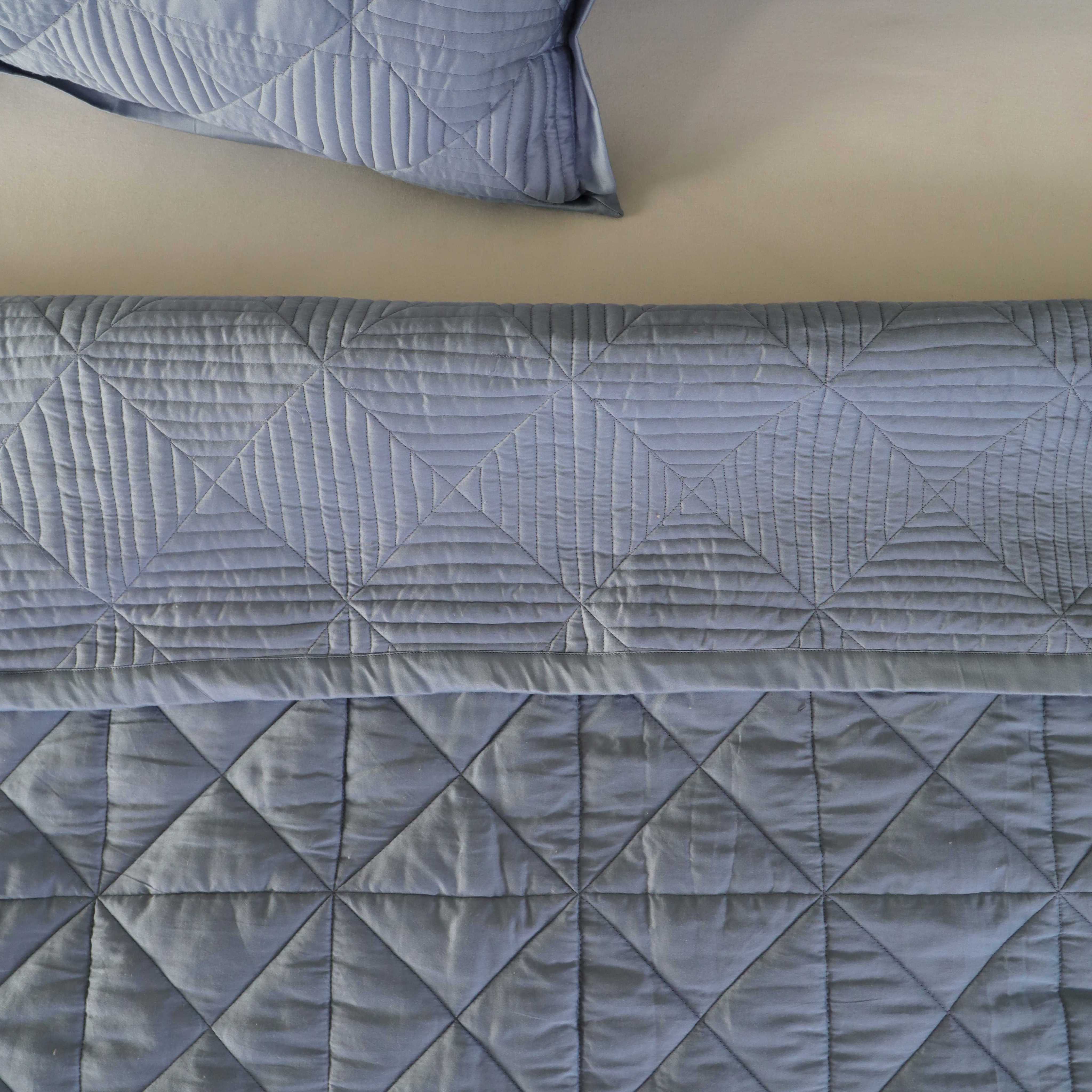 Close-up of the square geometric quilting on the dusty blue velvet fabric.