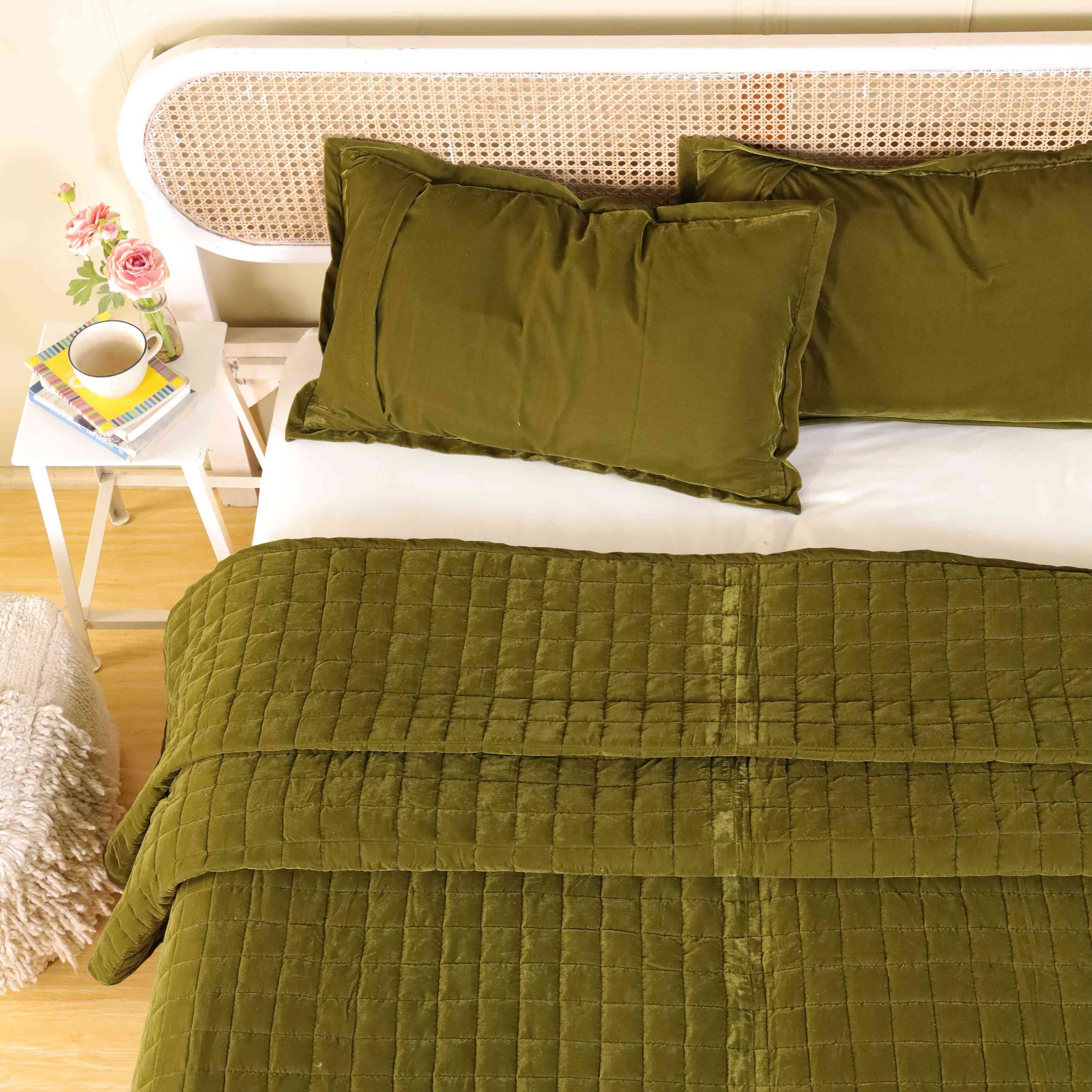 Modern luxury bedroom scene featuring deep green velvet bedding and neutral walls.