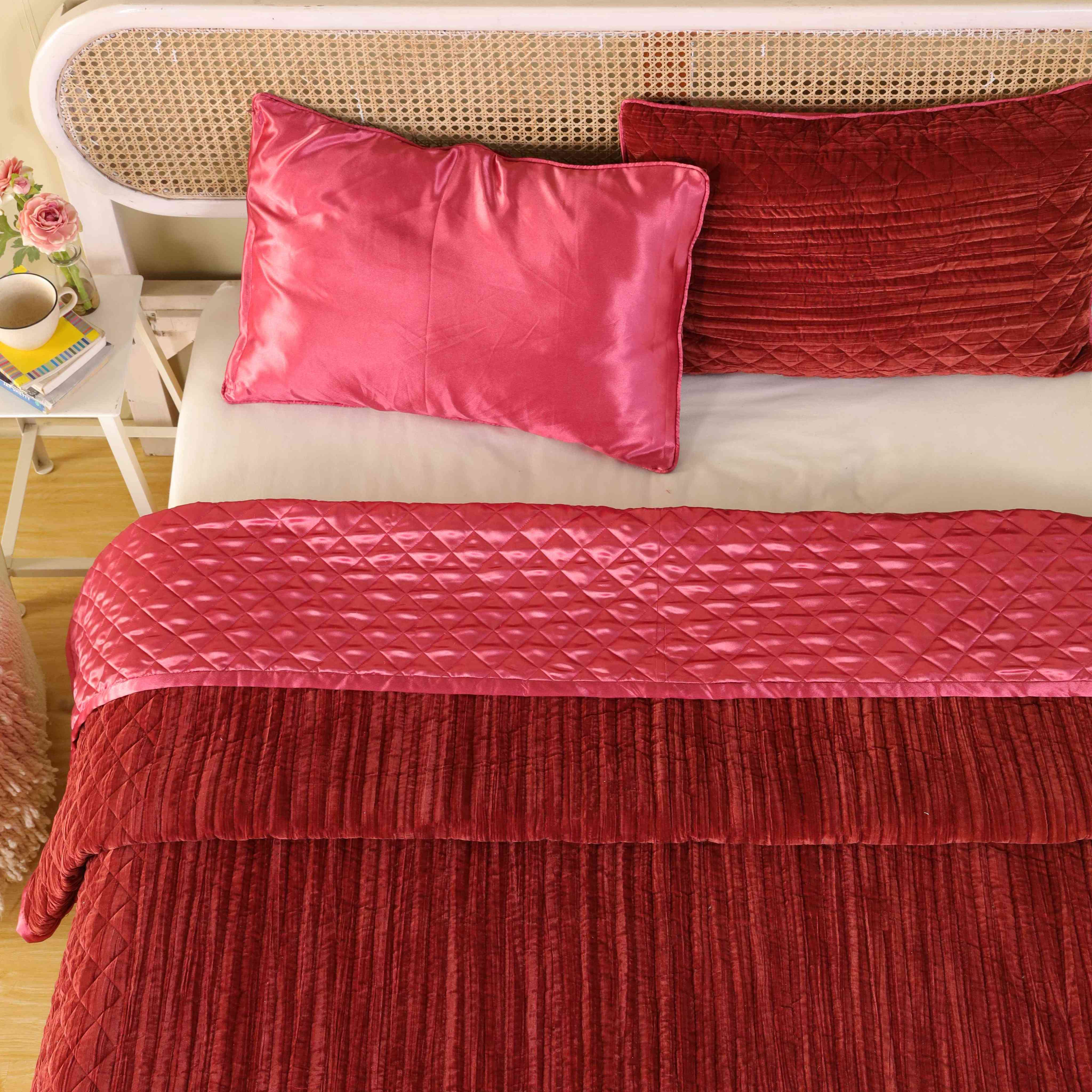 Overhead bedroom view featuring a reversible satin and velvet quilt with a rattan headboard.