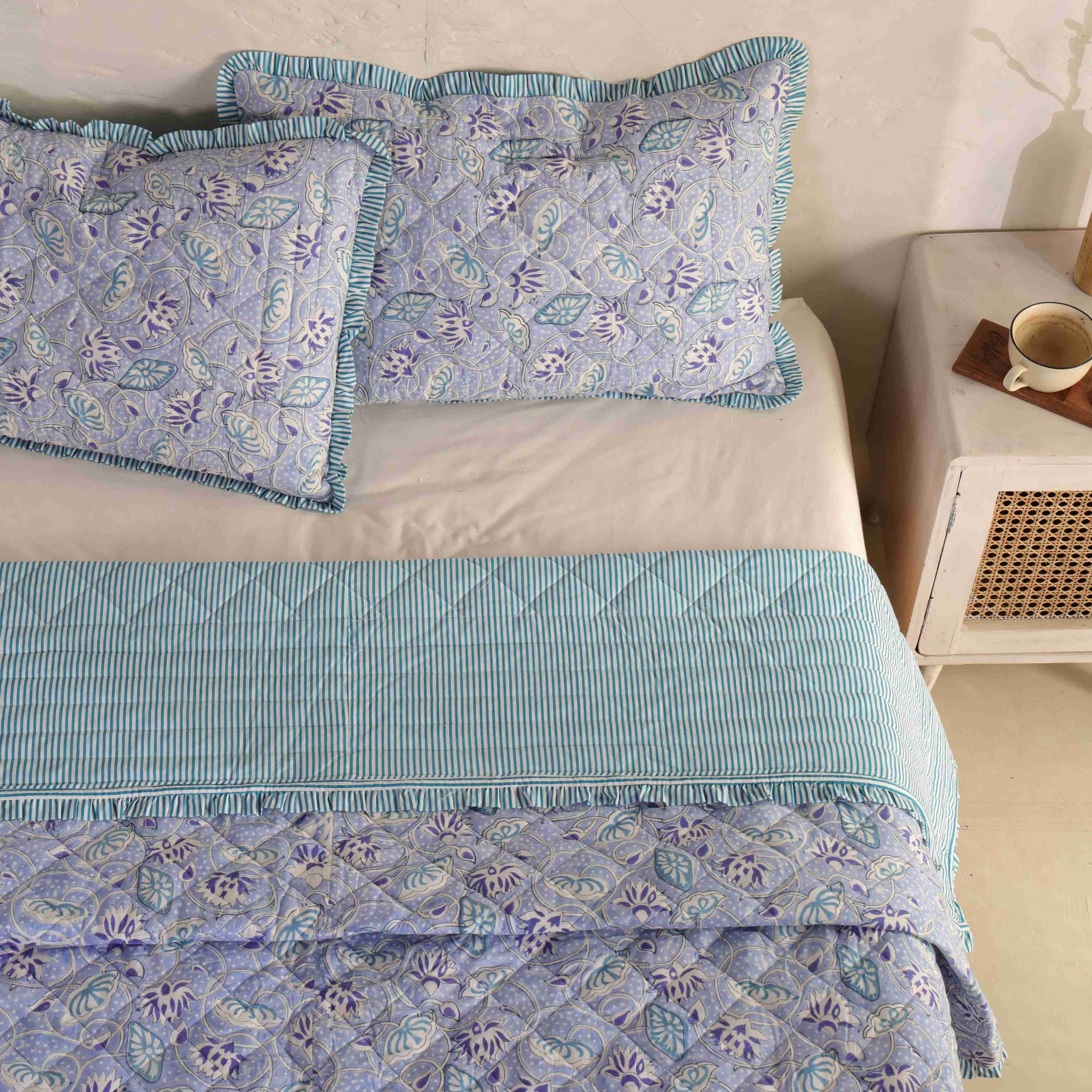 Modern airy bedroom interior featuring a periwinkle floral cotton quilt.