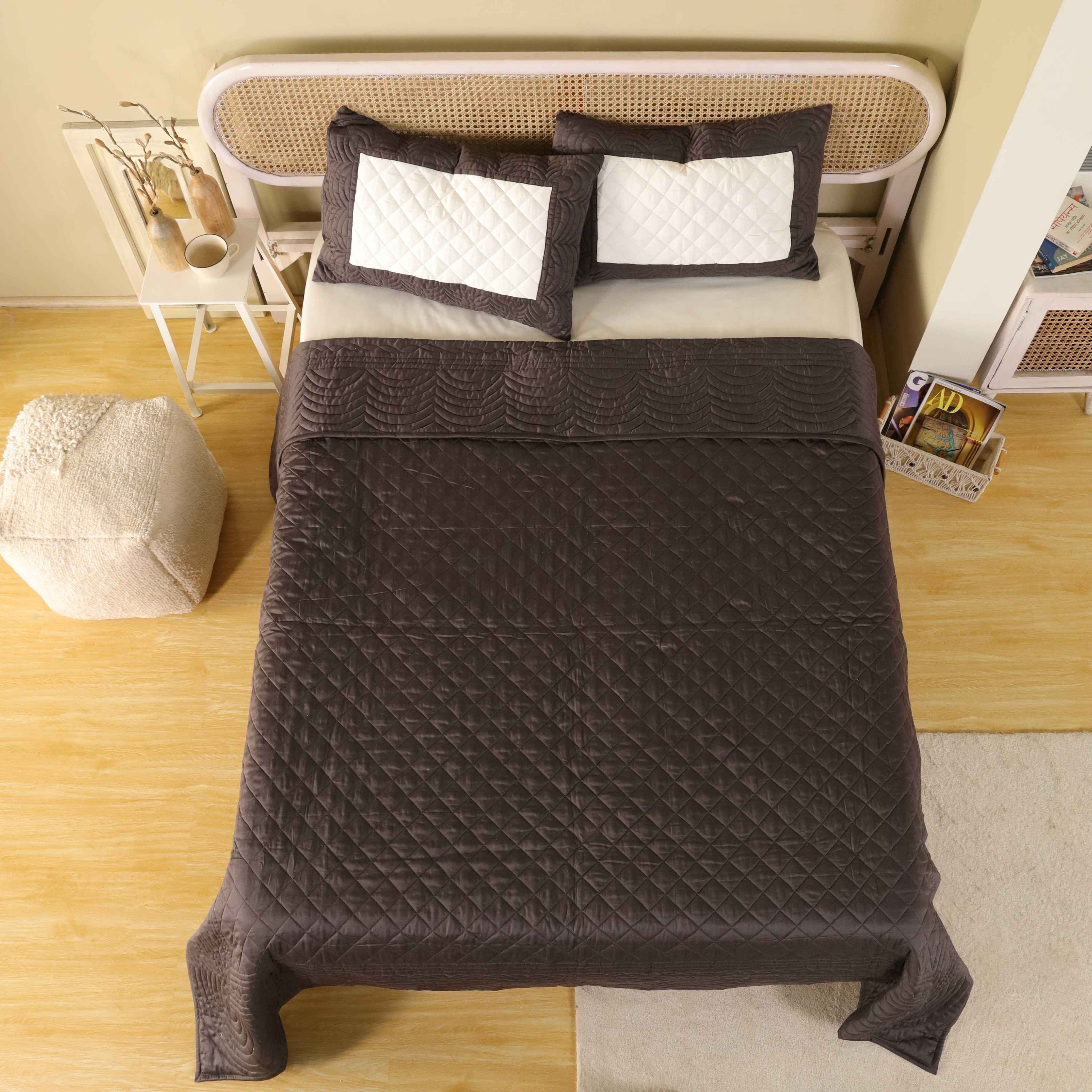 A styled modern bedroom featuring a chocolate satin quilt and minimalist neutral decor.