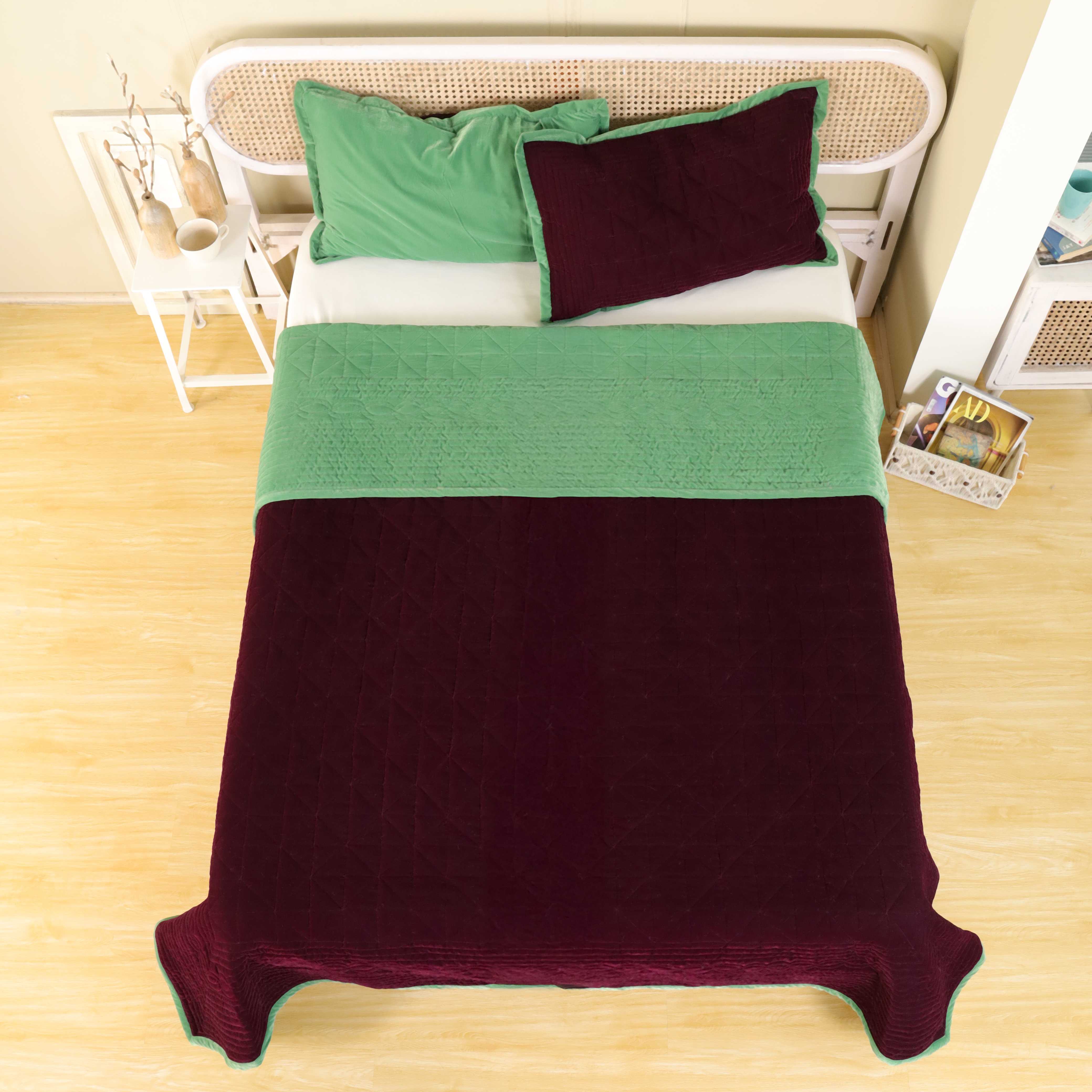 Luxury bedroom scene featuring a two-tone maroon and green reversible bedding set.