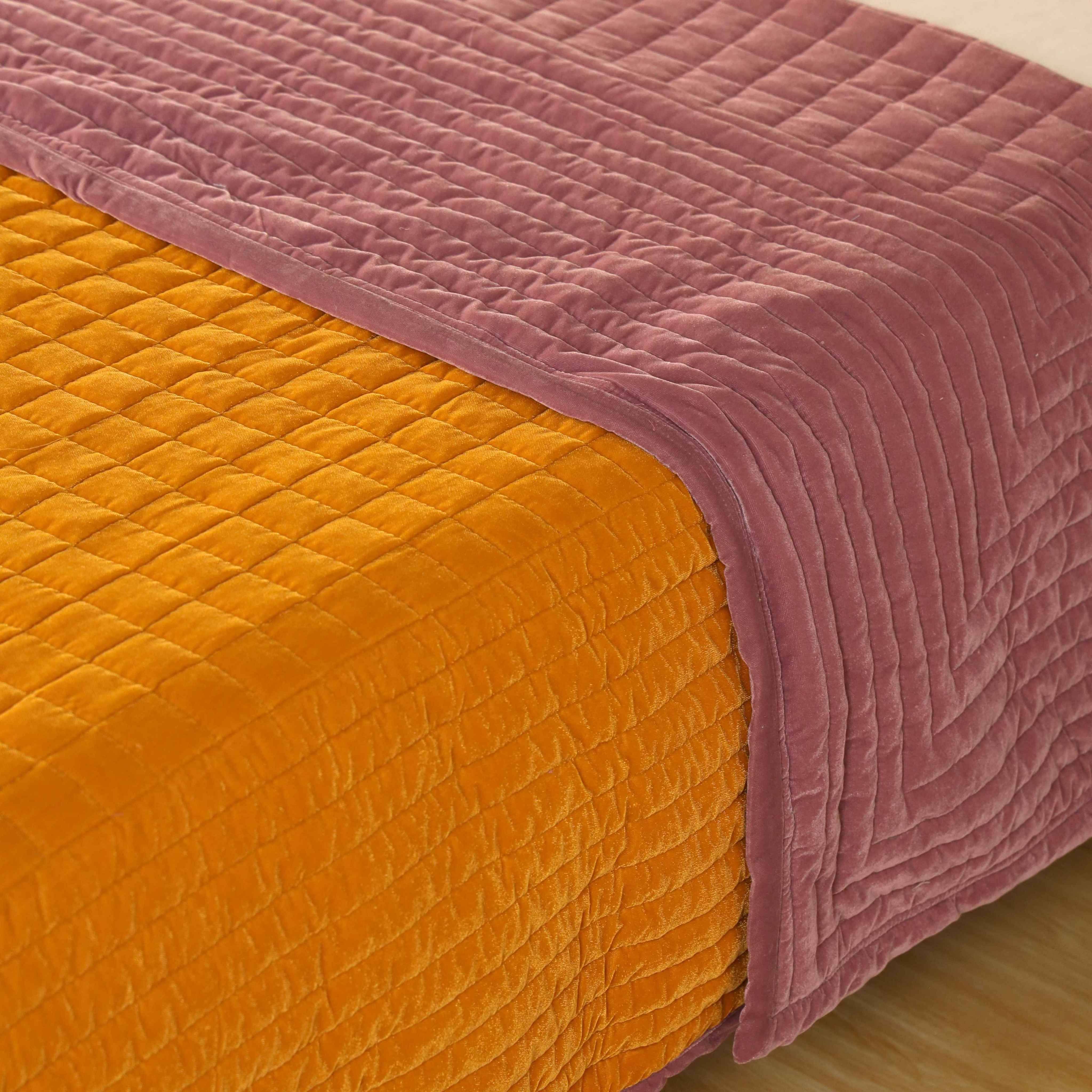 Luxury reversible bedding set in yellow and pink styled in a bright modern bedroom with a cane headboard.