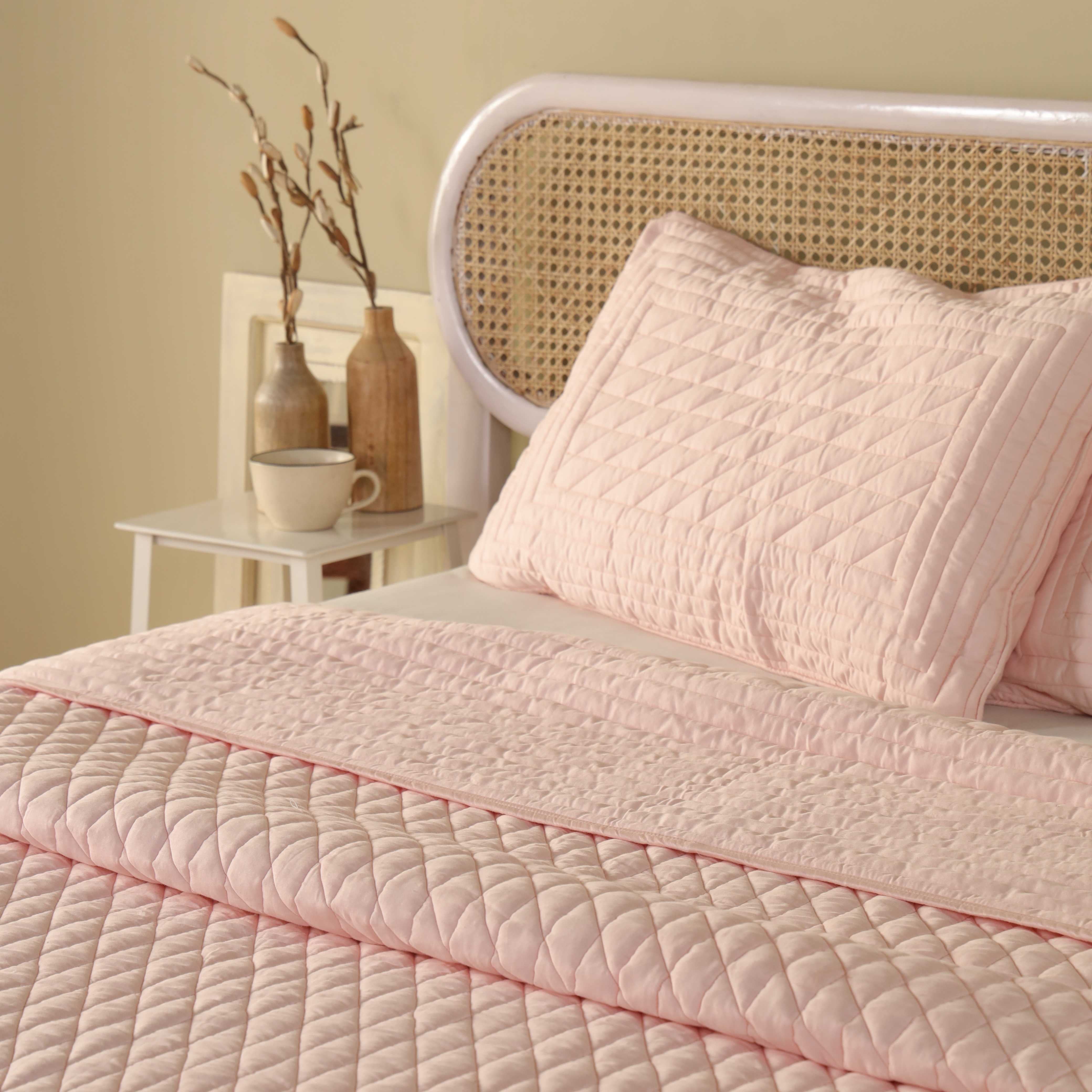 Two matching blush pink satin pillow covers with diagonal quilted patterns.