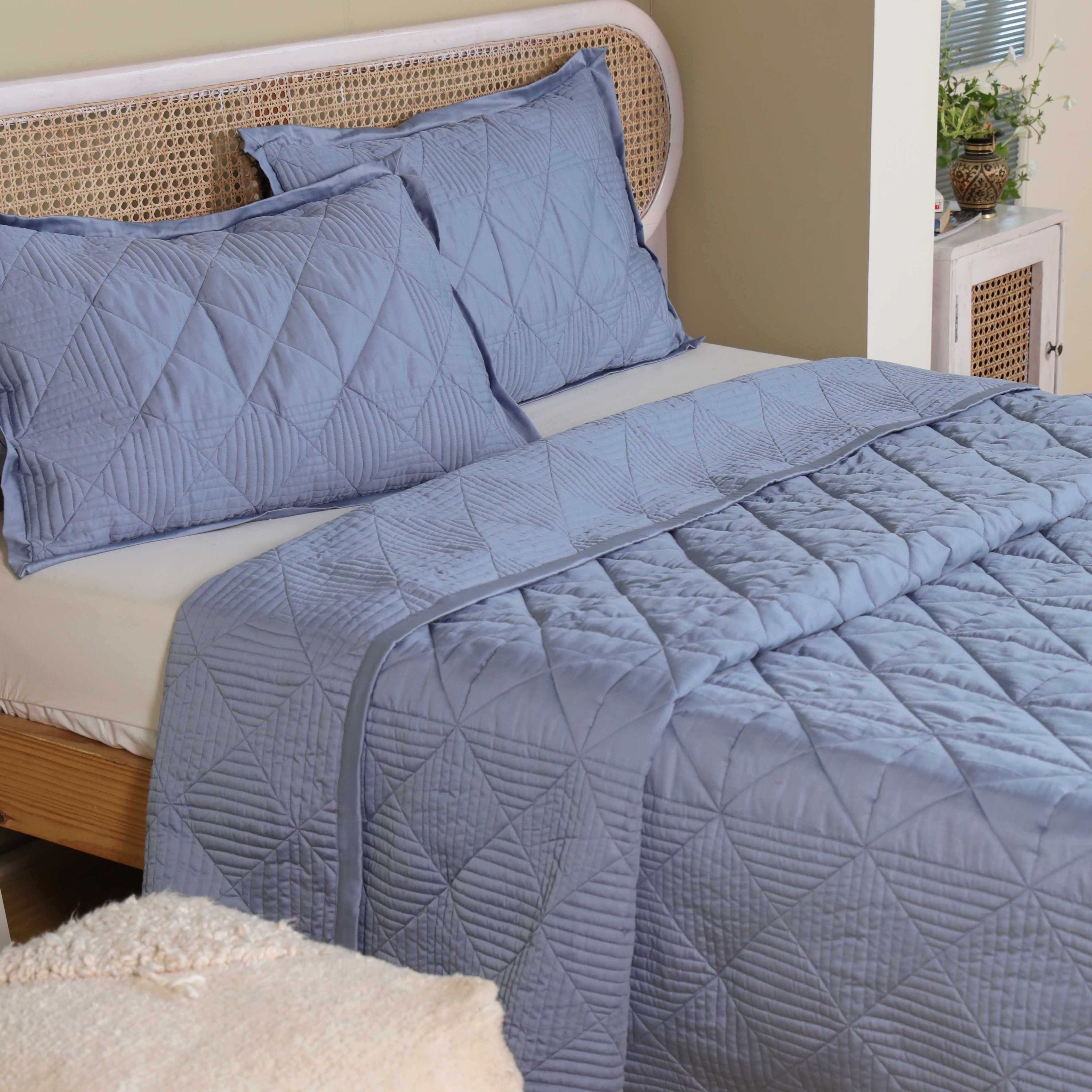 Two matching dusty blue velvet pillow shams with geometric quilting.