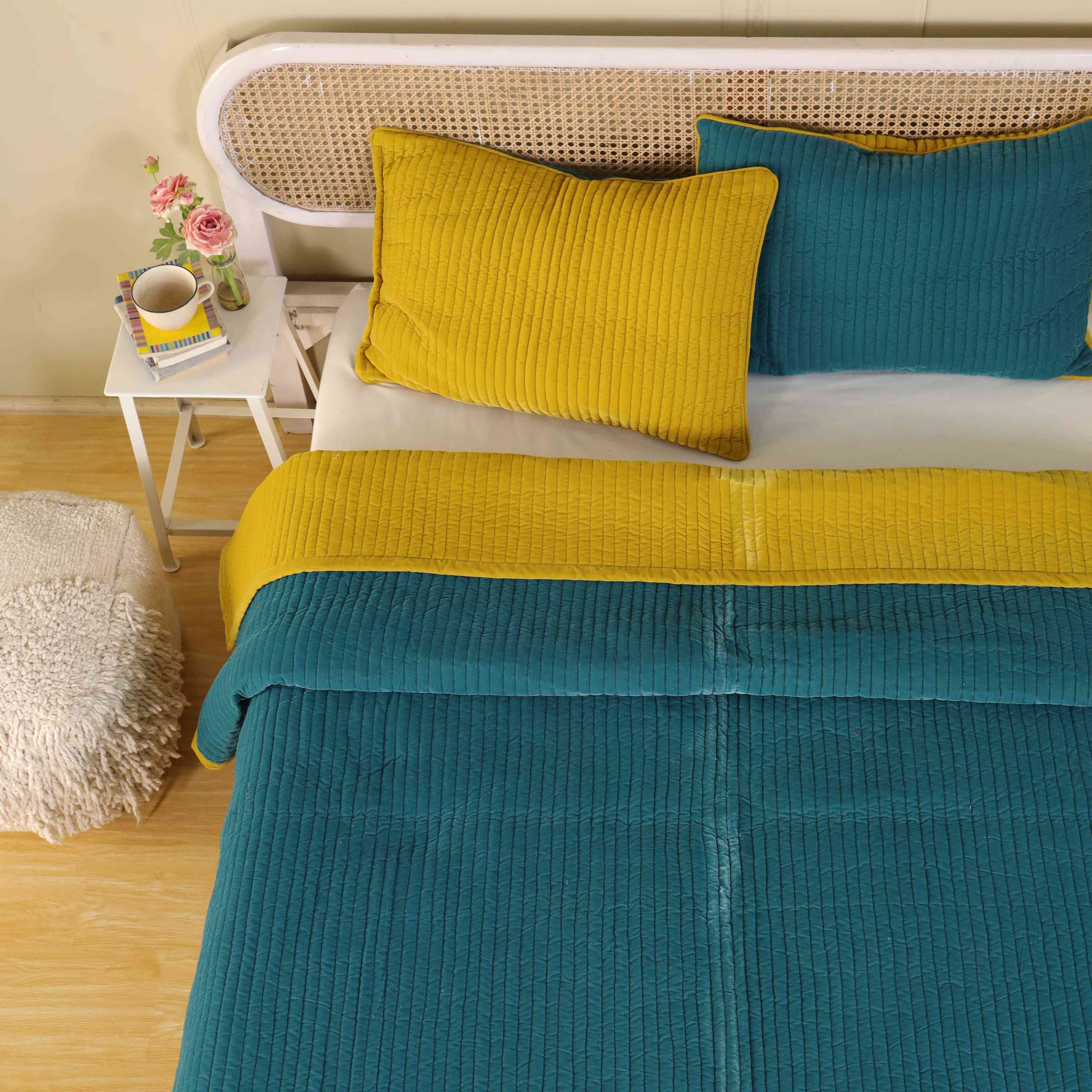 Top-down view of a modern bedroom styled with a reversible teal and mustard velvet duvet set.