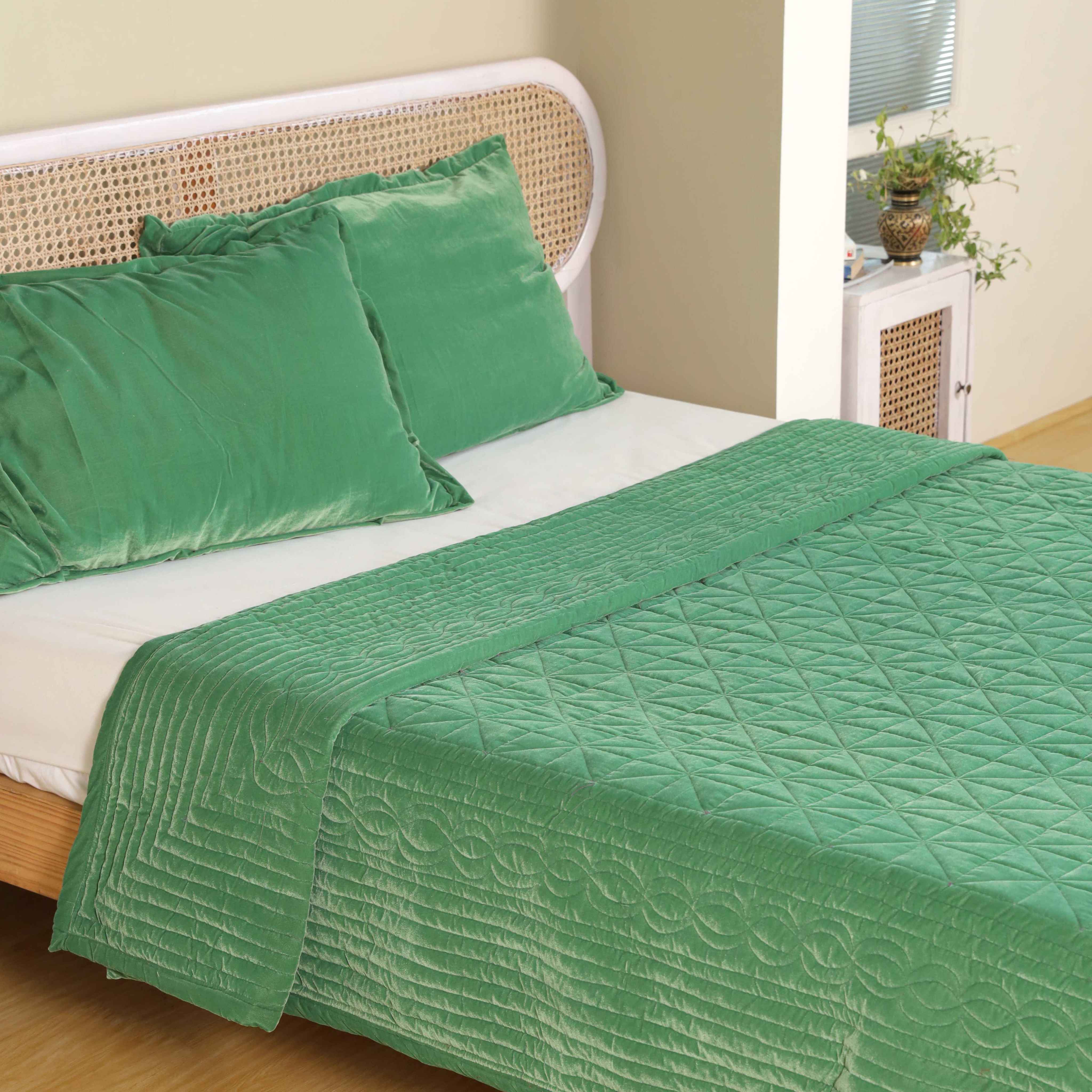 Lifestyle view of a cozy bedroom featuring a jewel-toned emerald green satin duvet set.