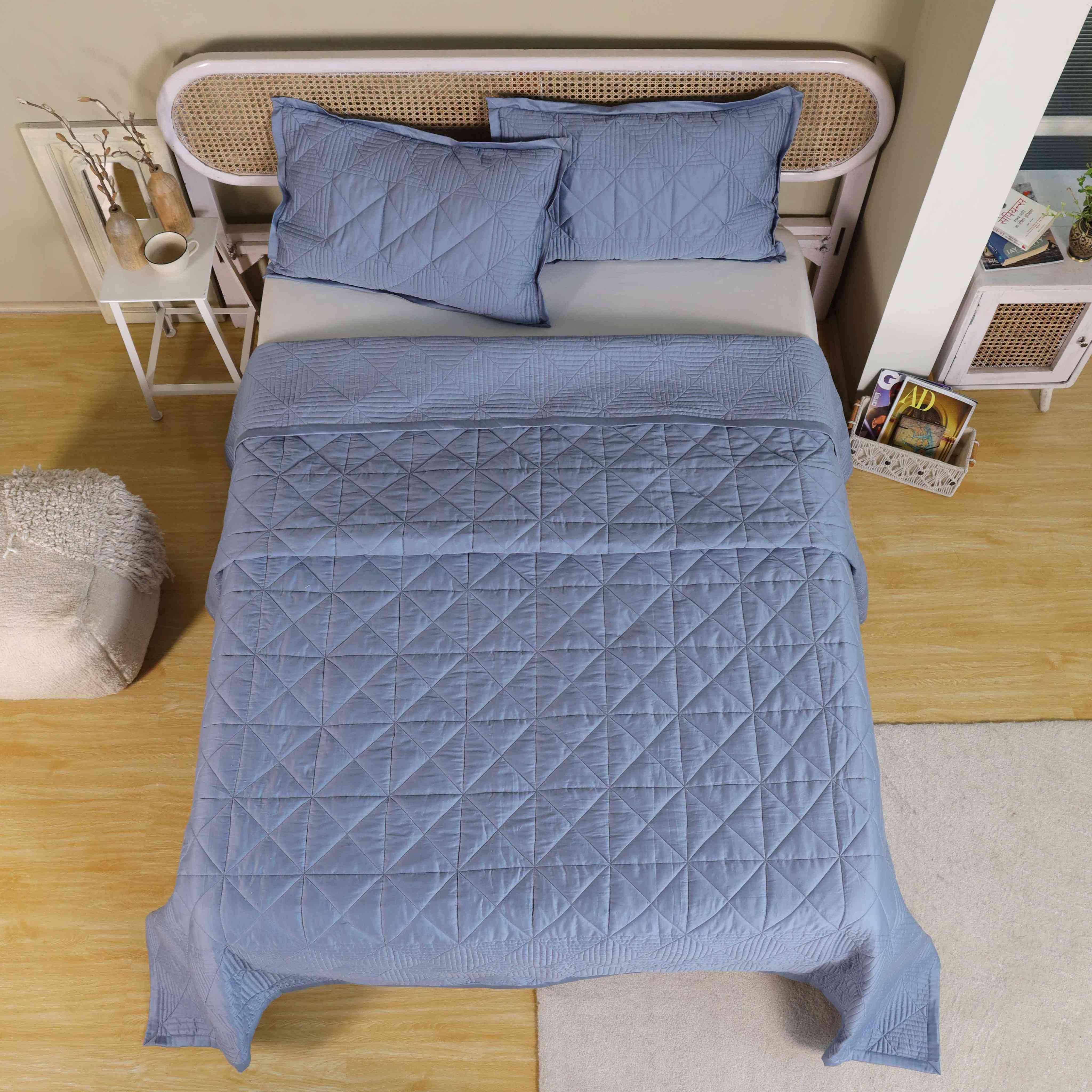 A styled modern bedroom featuring a blue velvet quilt and neutral accessories.