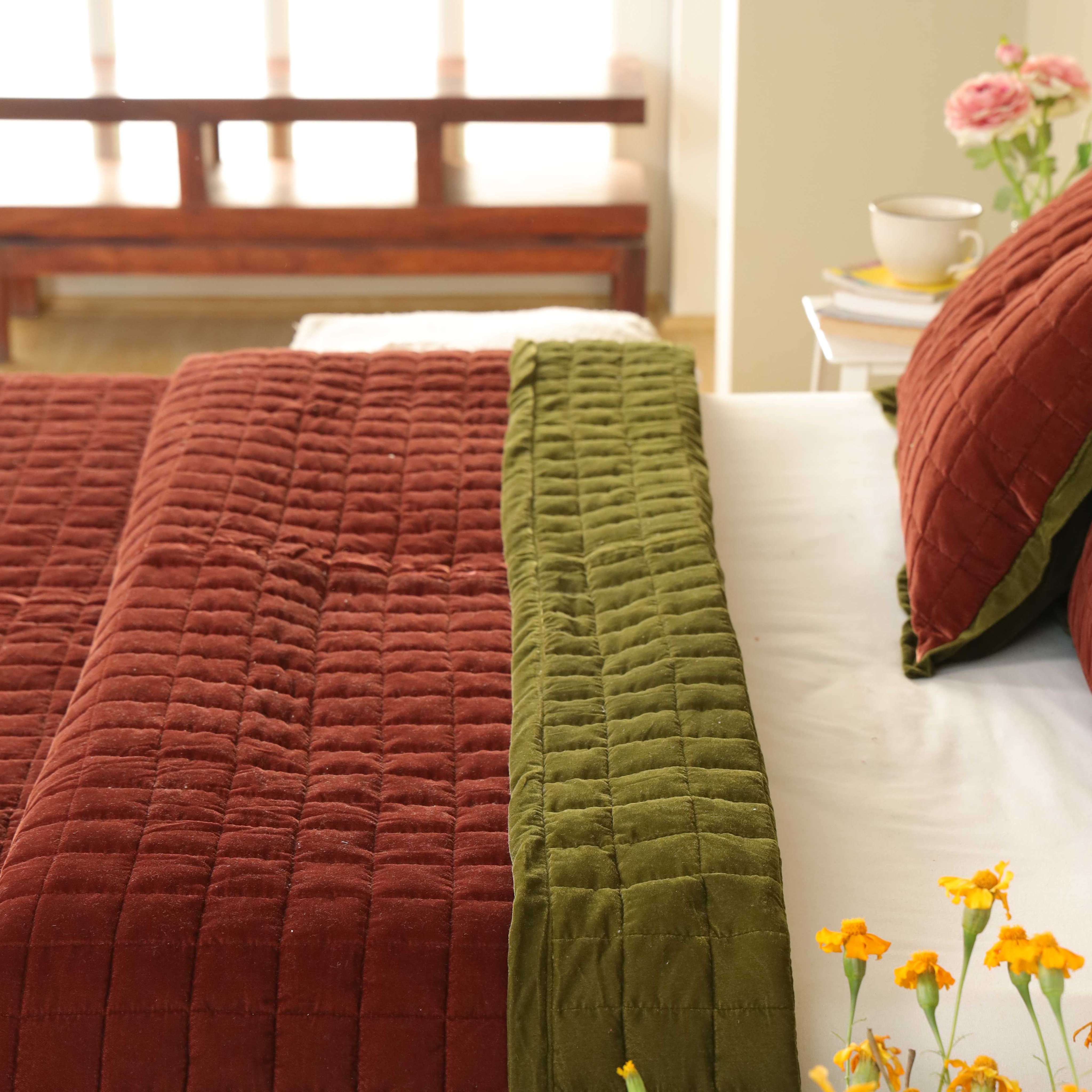 Luxury reversible bedding featuring one side in brick red and the other in dark olive green.