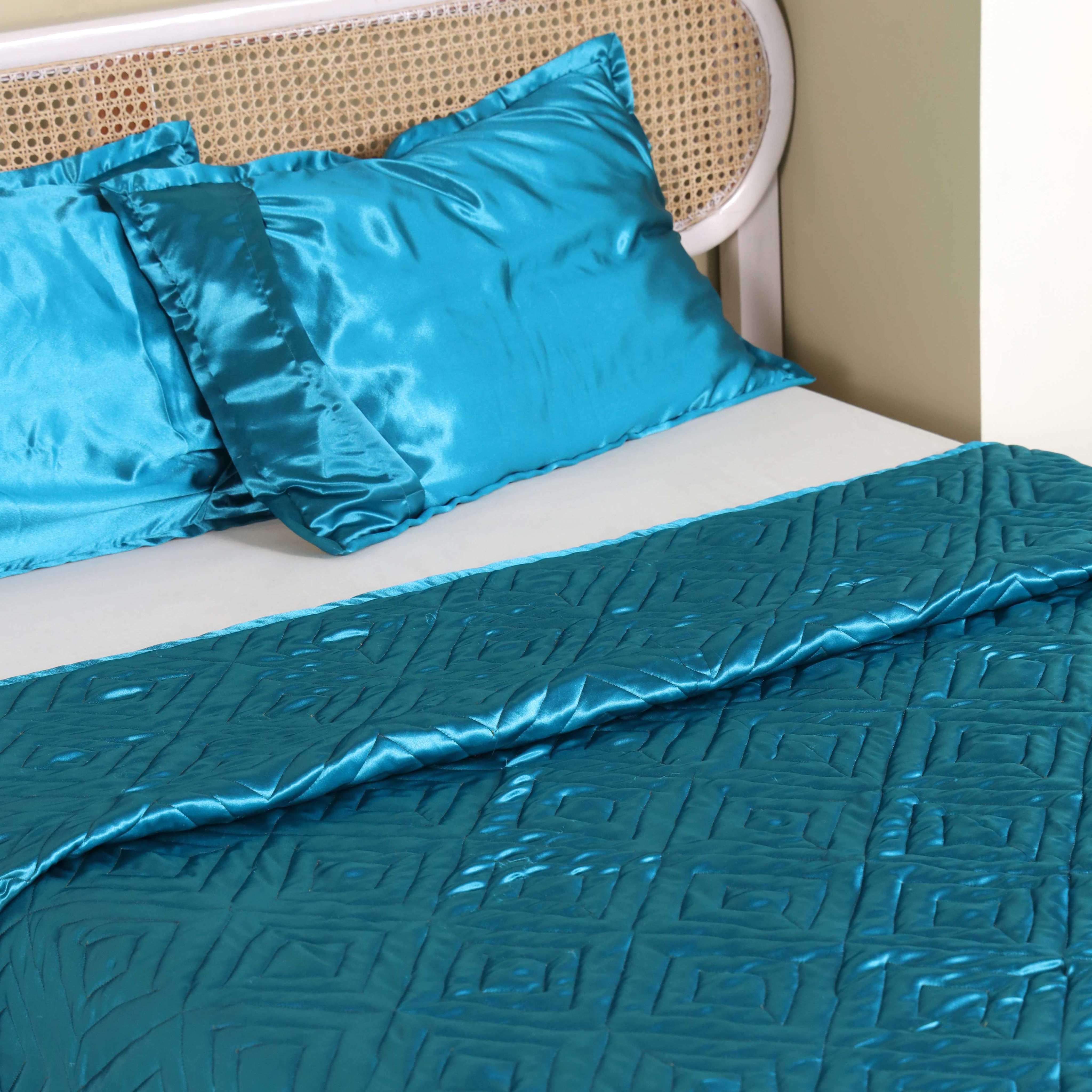 Modern bedroom styling featuring a teal satin quilt set and white cane headboard.