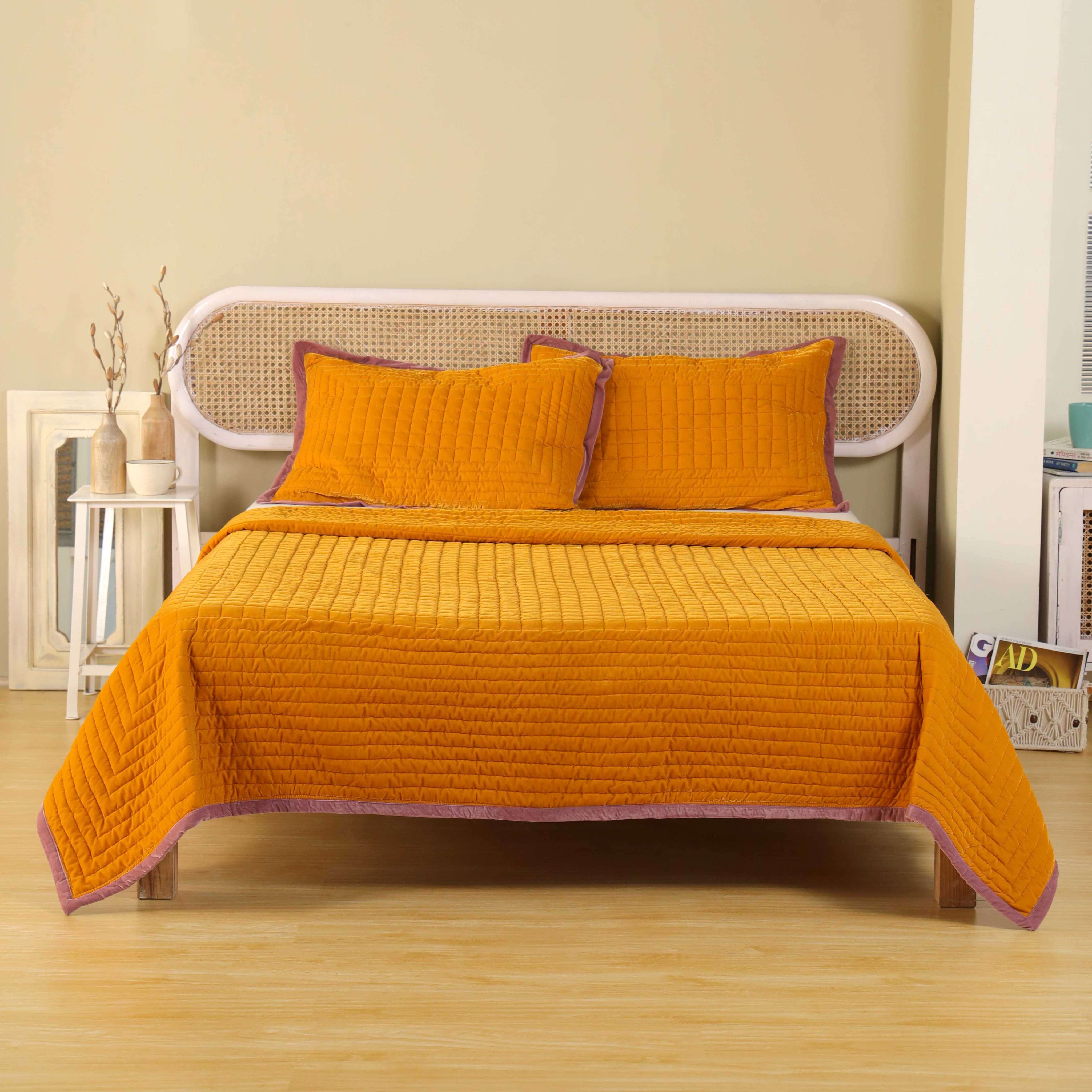 Two mustard yellow velvet pillow covers featuring vertical and square quilting with mauve piping.