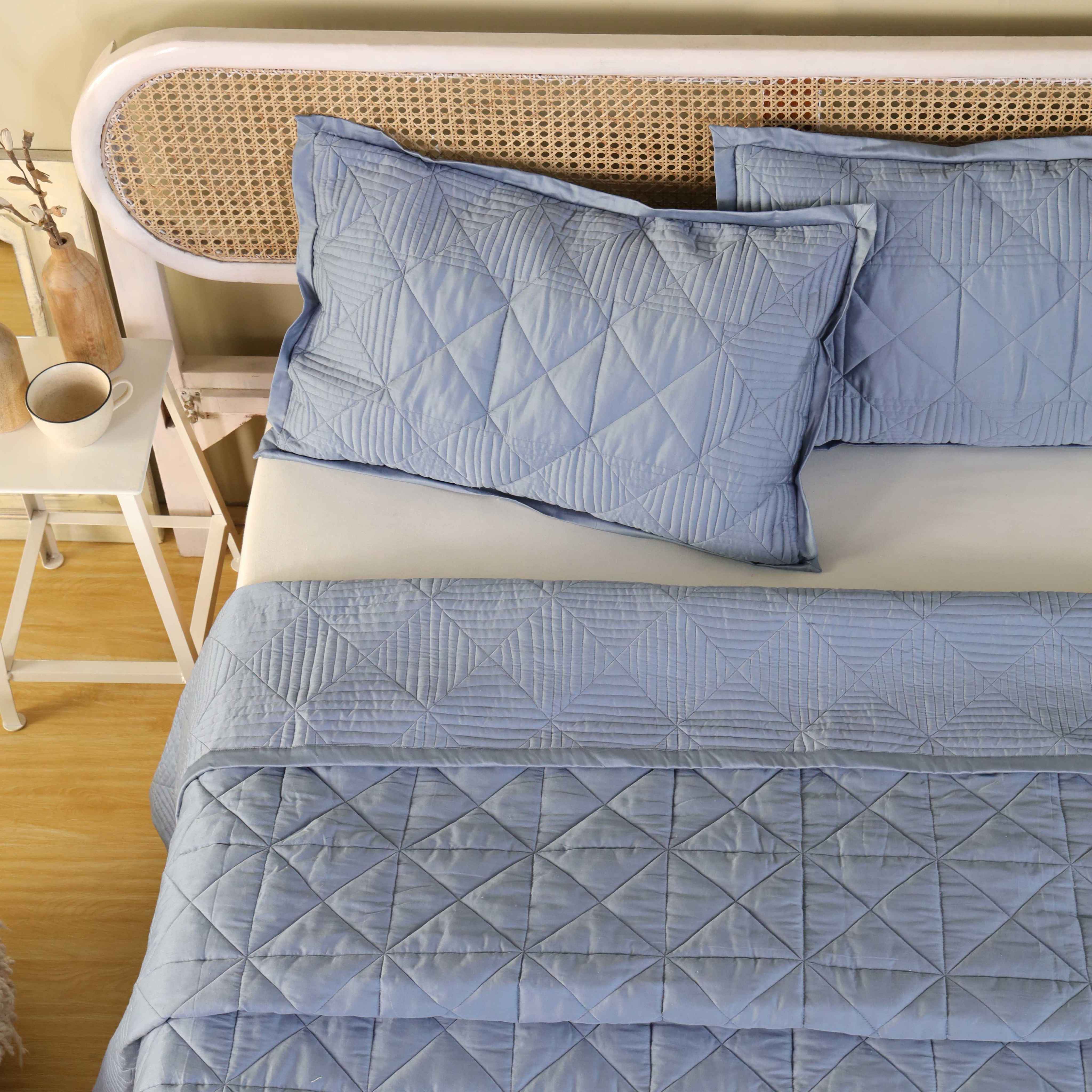 The edge of a dusty blue velvet quilt showing the thickness and high-quality drape.