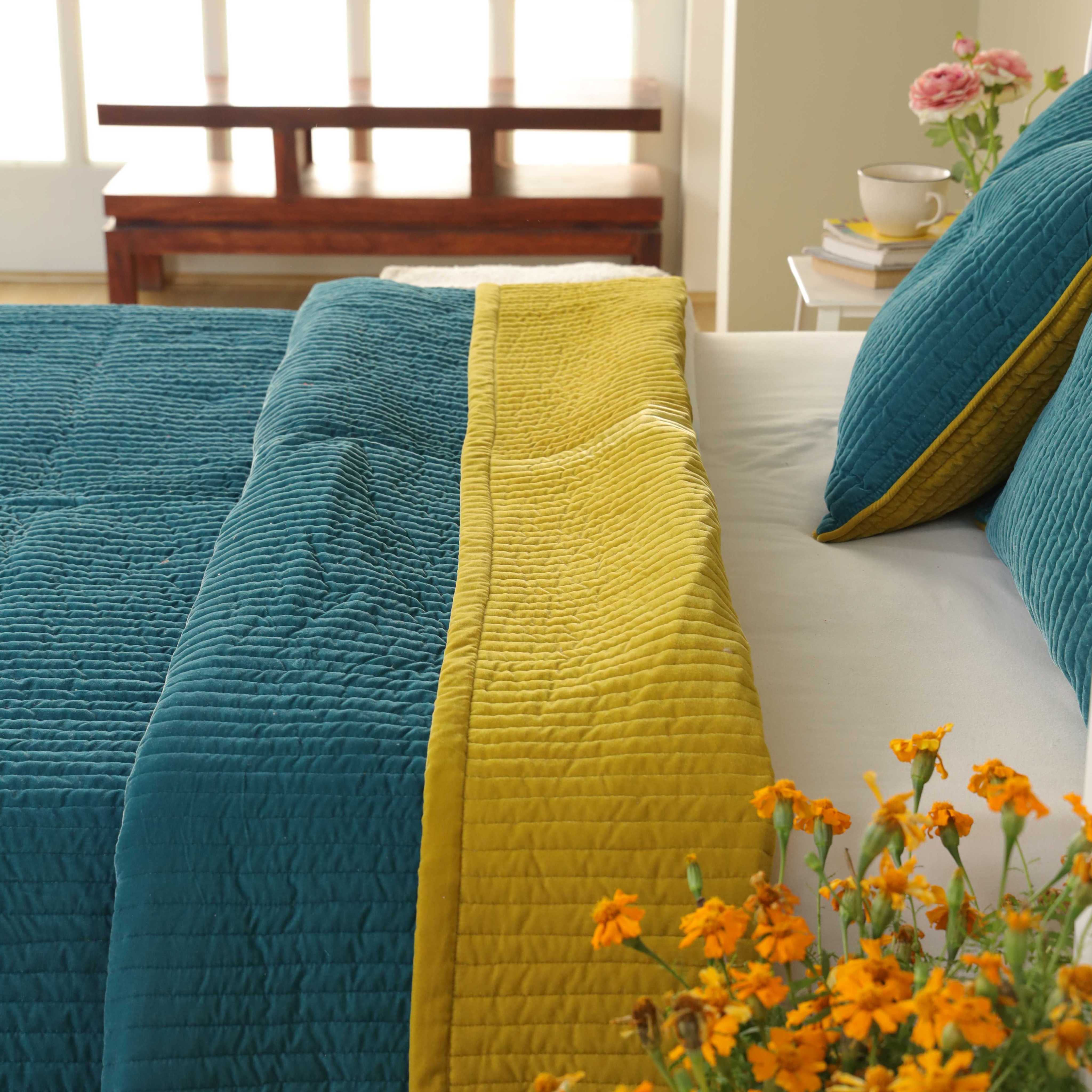 Reversible velvet duvet cover showing both teal blue and mustard yellow sides with vertical quilting.