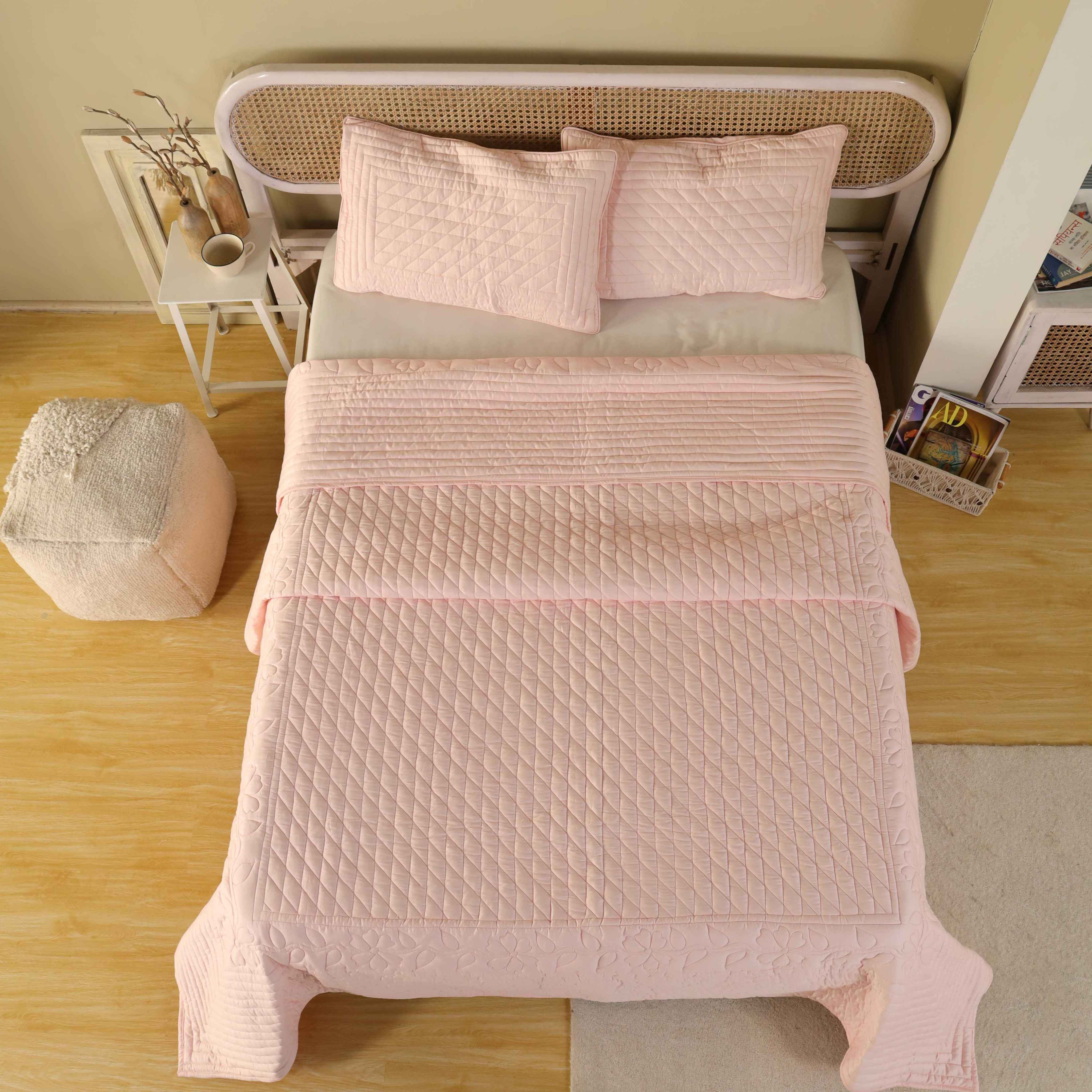 A styled bedroom featuring a pink satin quilt and neutral decor for a romantic aesthetic.