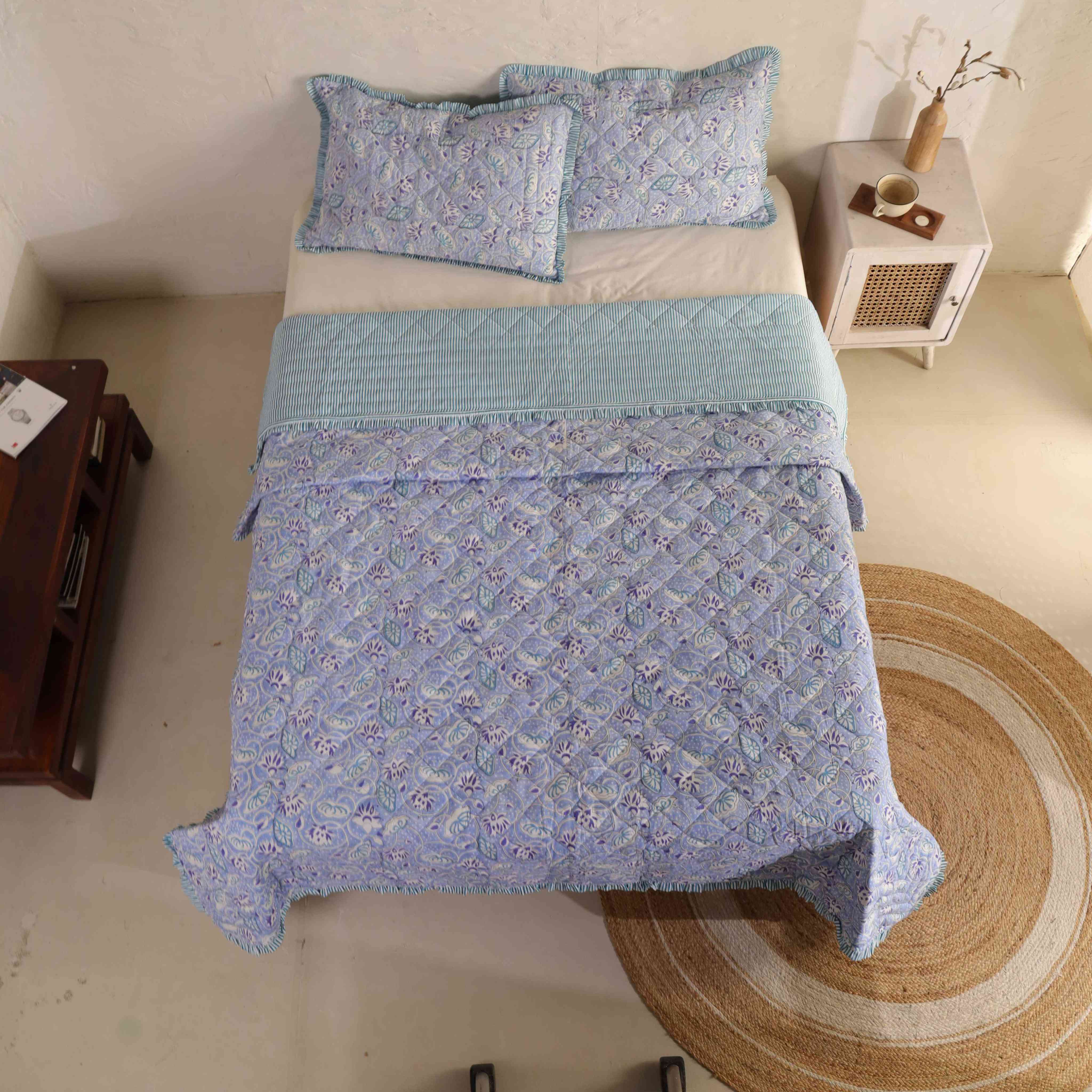 Two matching periwinkle blue floral pillow covers with striped ruffle accents.