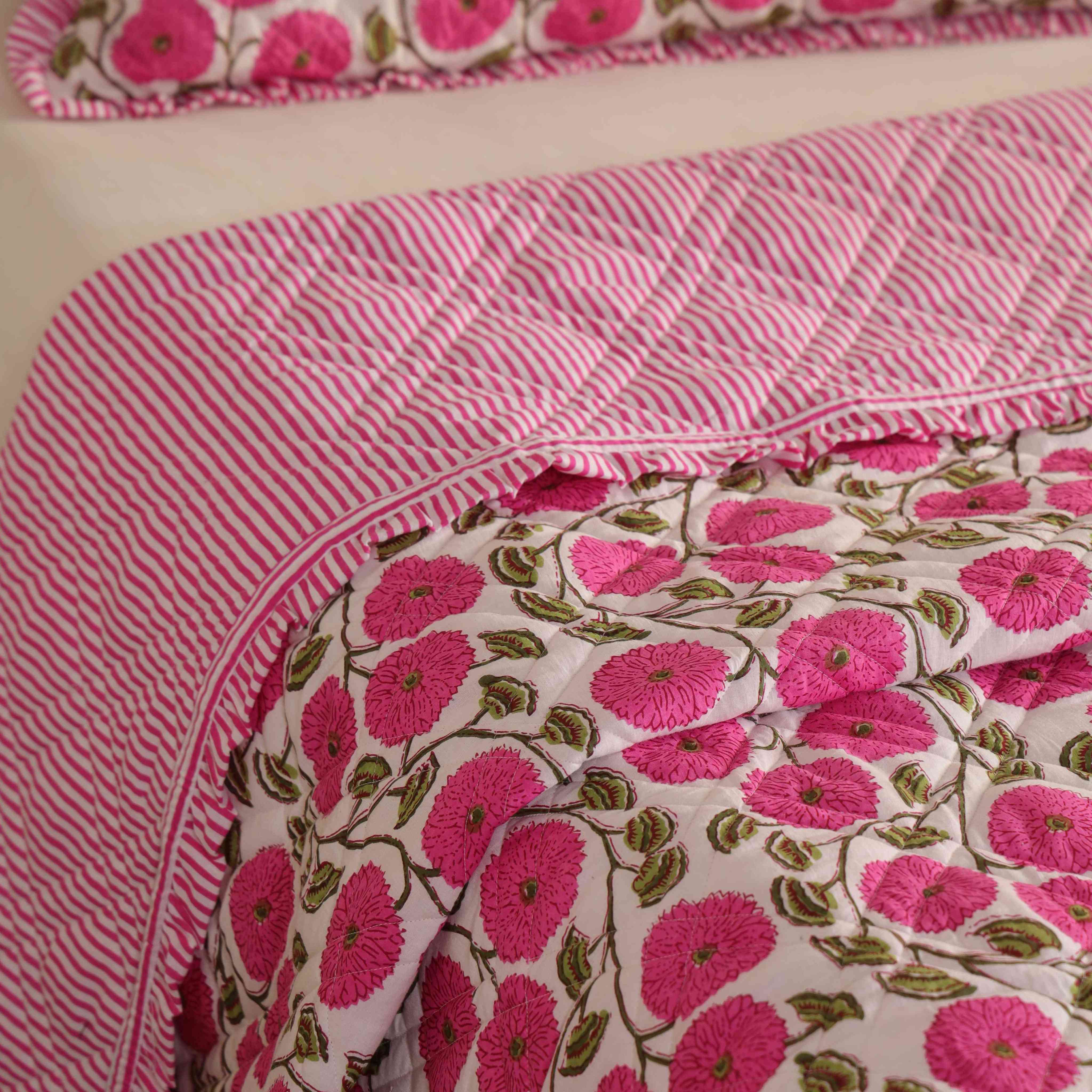 Two matching pink floral pillow covers with striped ruffle accents.