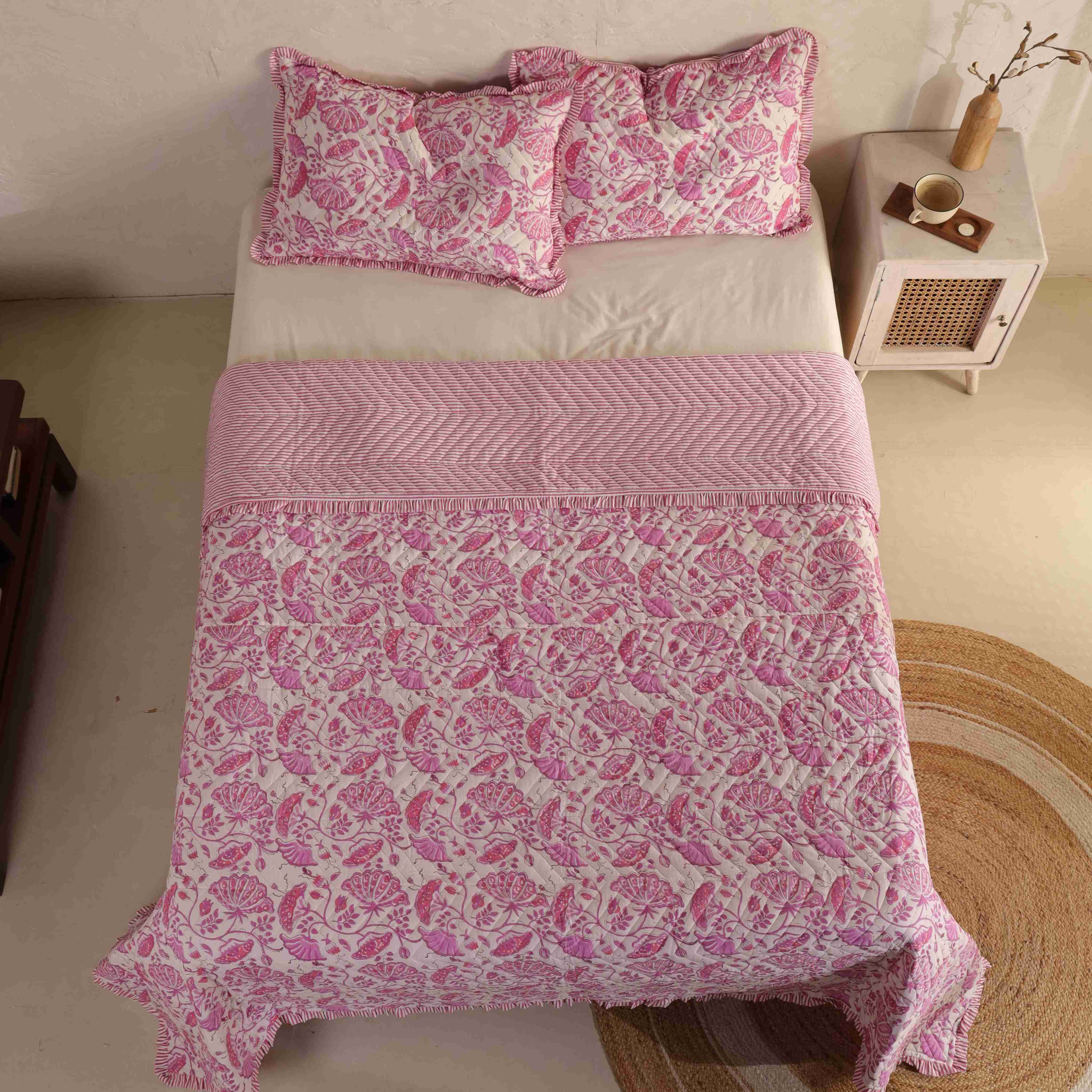 Two matching pink floral velvet pillow covers with striped ruffle accents.