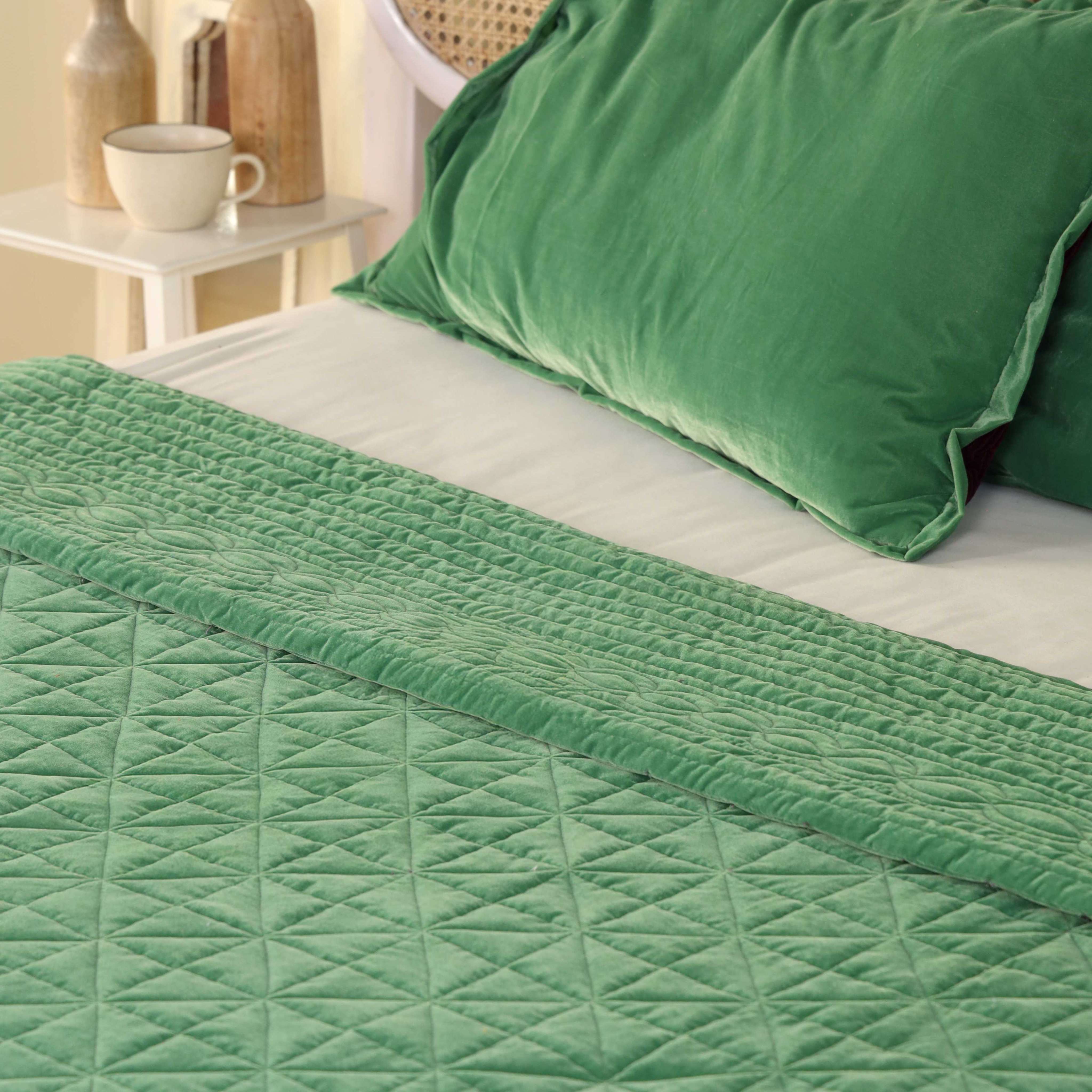 Two matching emerald green satin pillow covers featuring decorative quilted stitching.