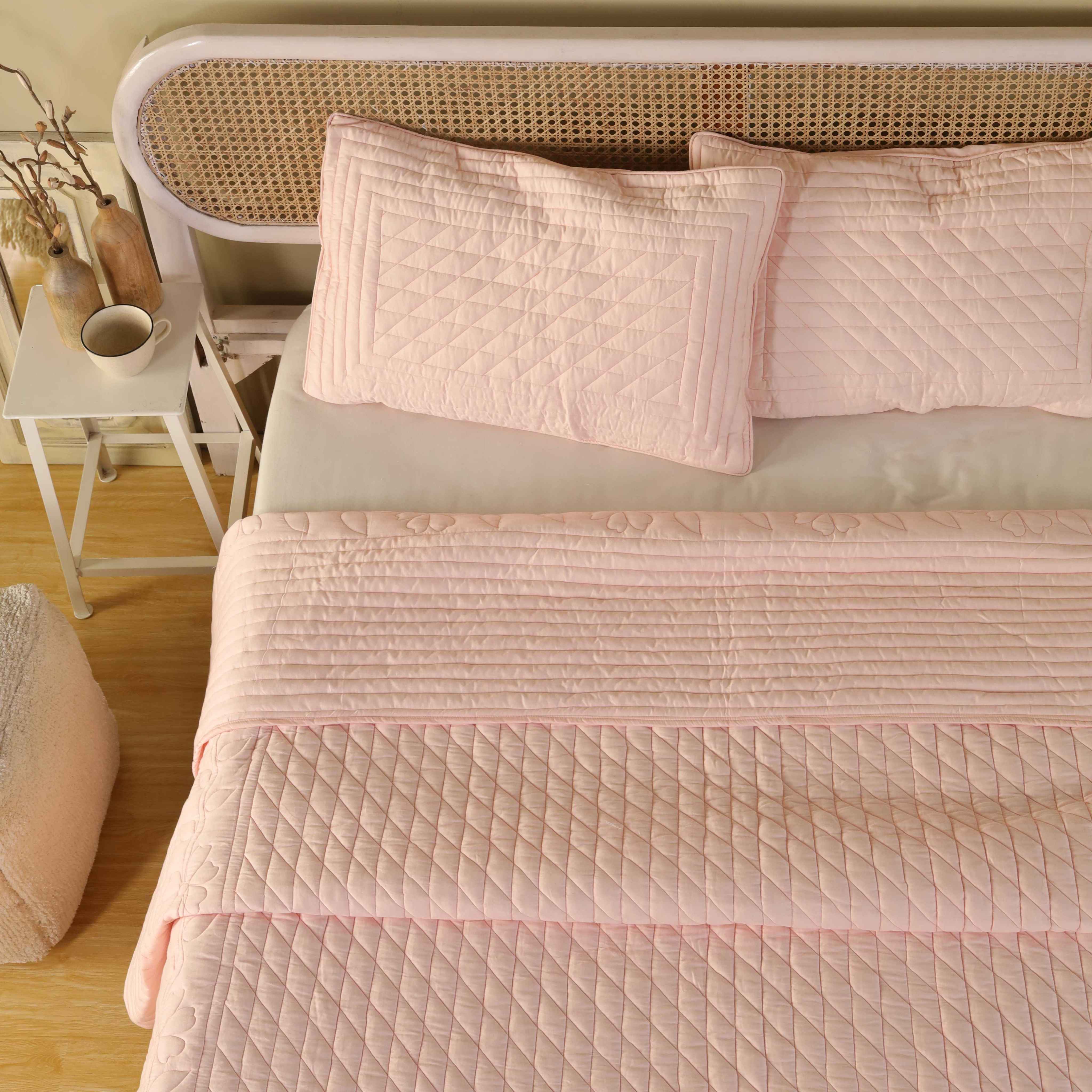 The edge of the blush pink satin quilt showing the drape and thickness of the fabric.