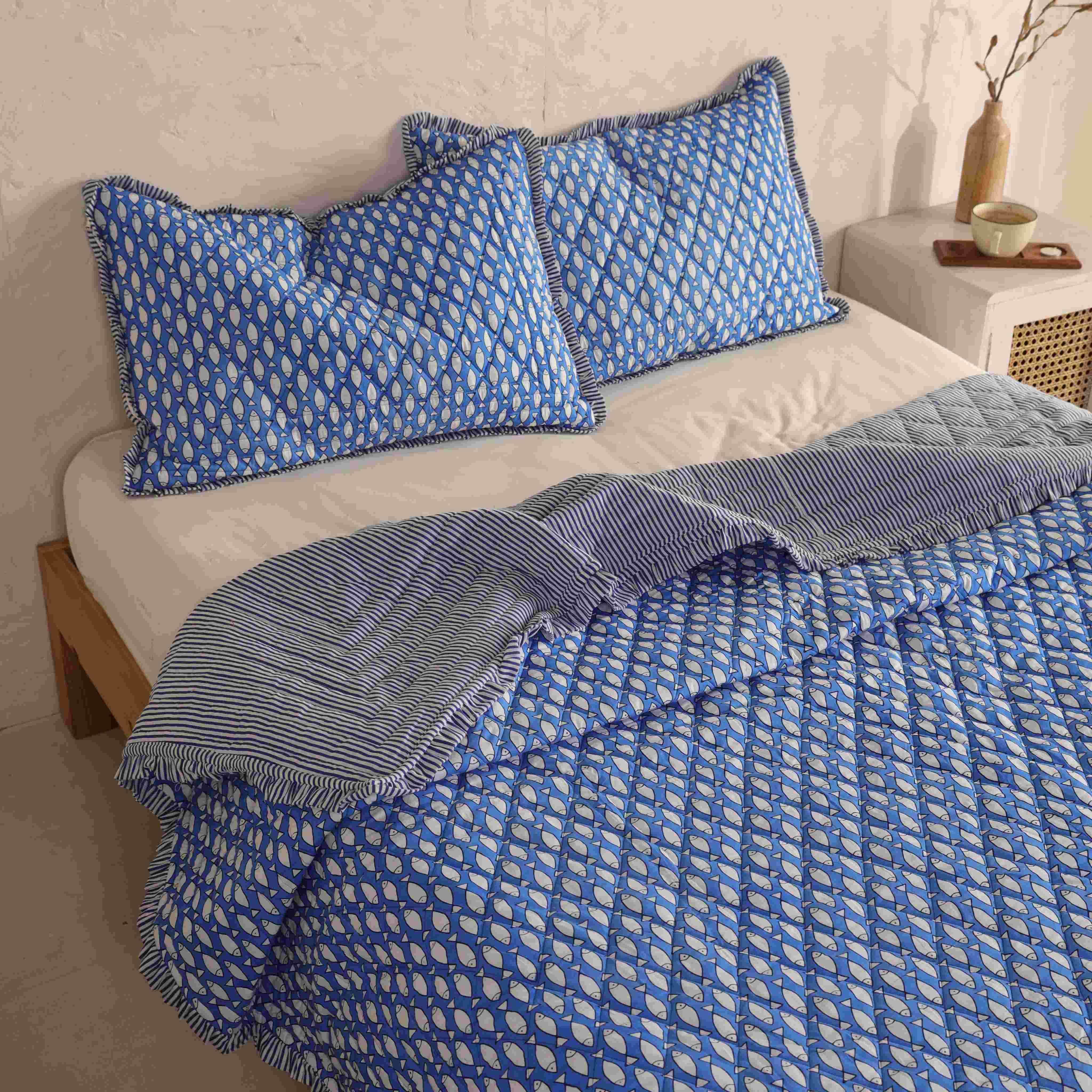 Two matching blue velvet pillow covers with navy and white striped ruffle accents.