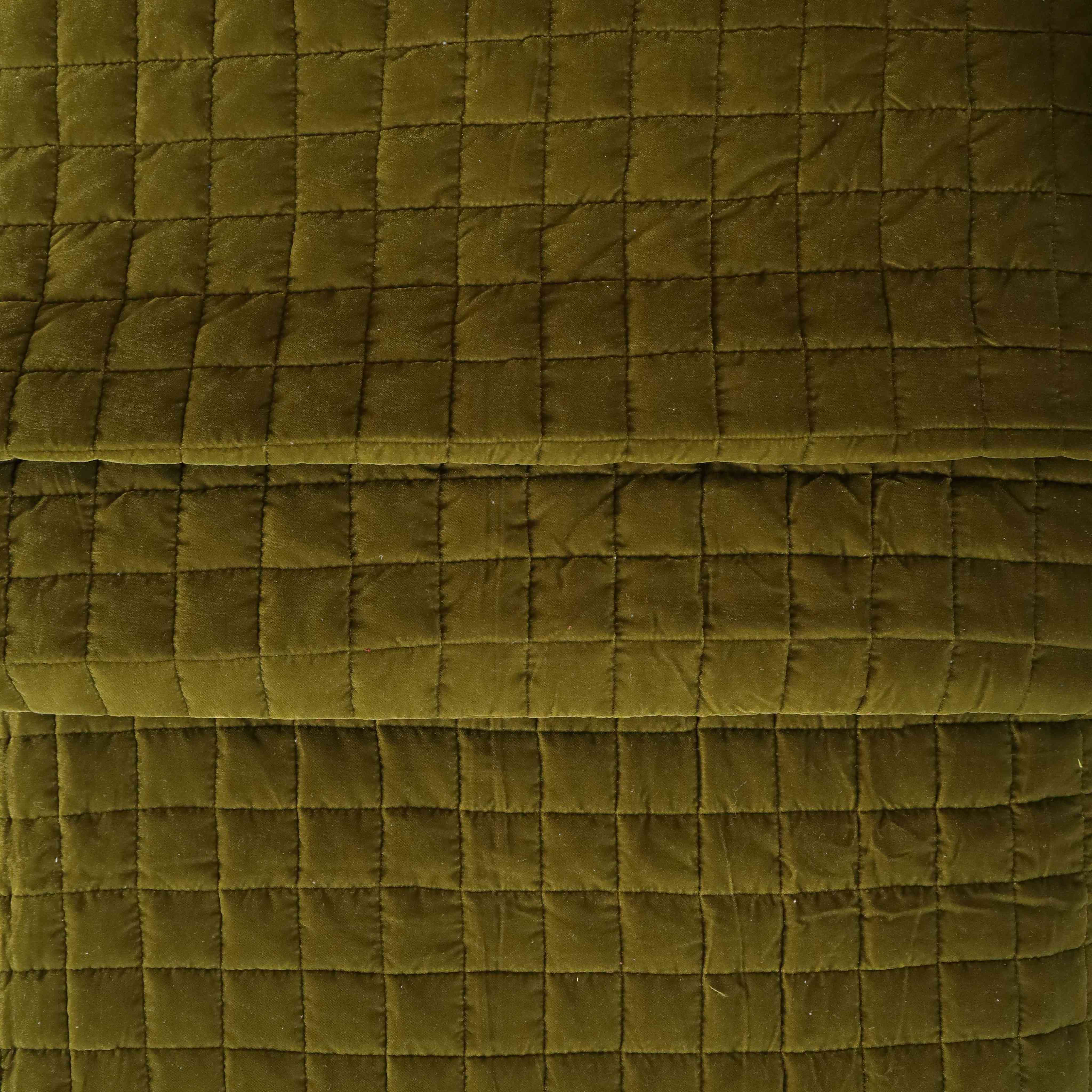 Two matching velvet pillow covers in dark olive green displayed on a minimalist bed.