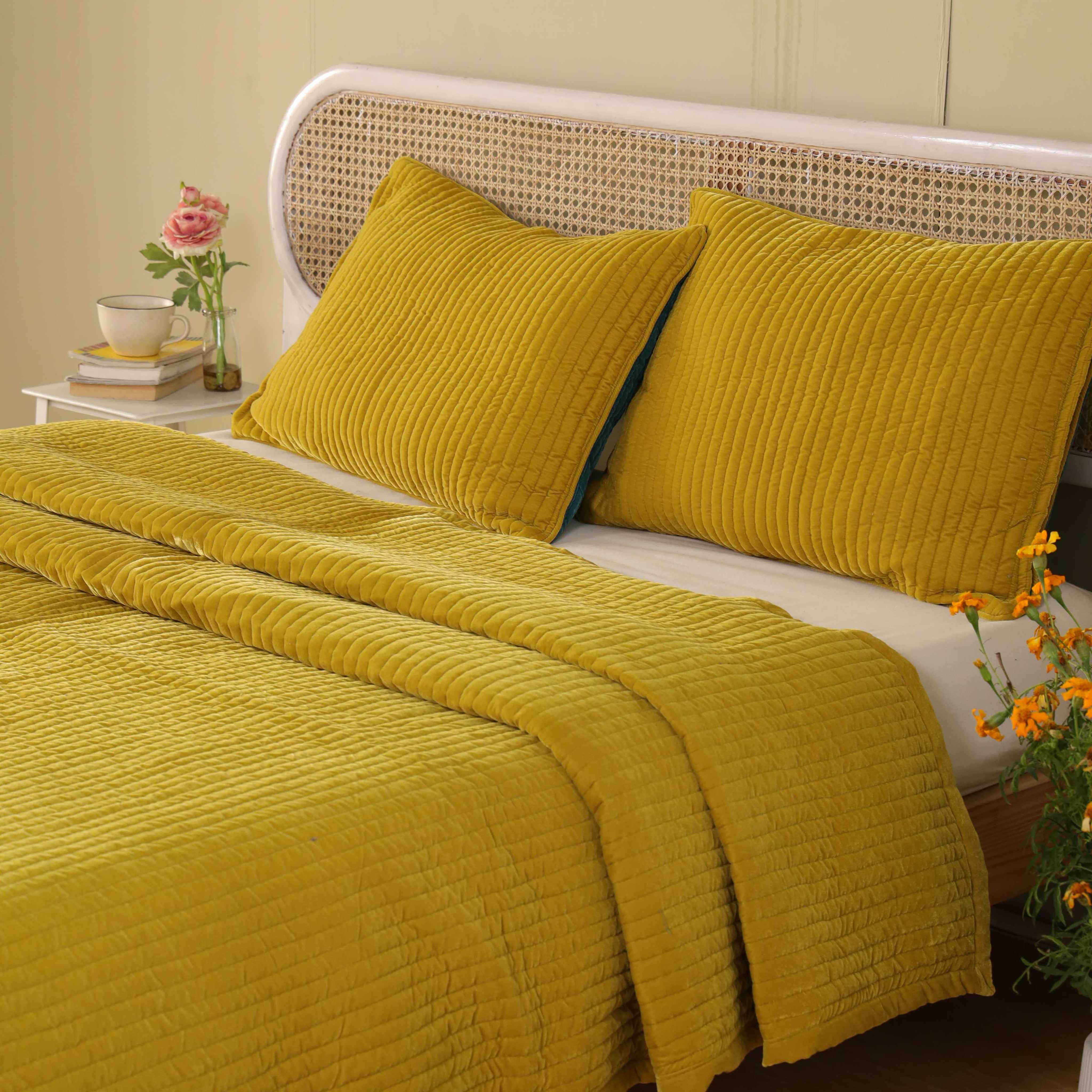 Two mustard yellow velvet pillow covers with vertical channel quilting shown against a neutral background.
