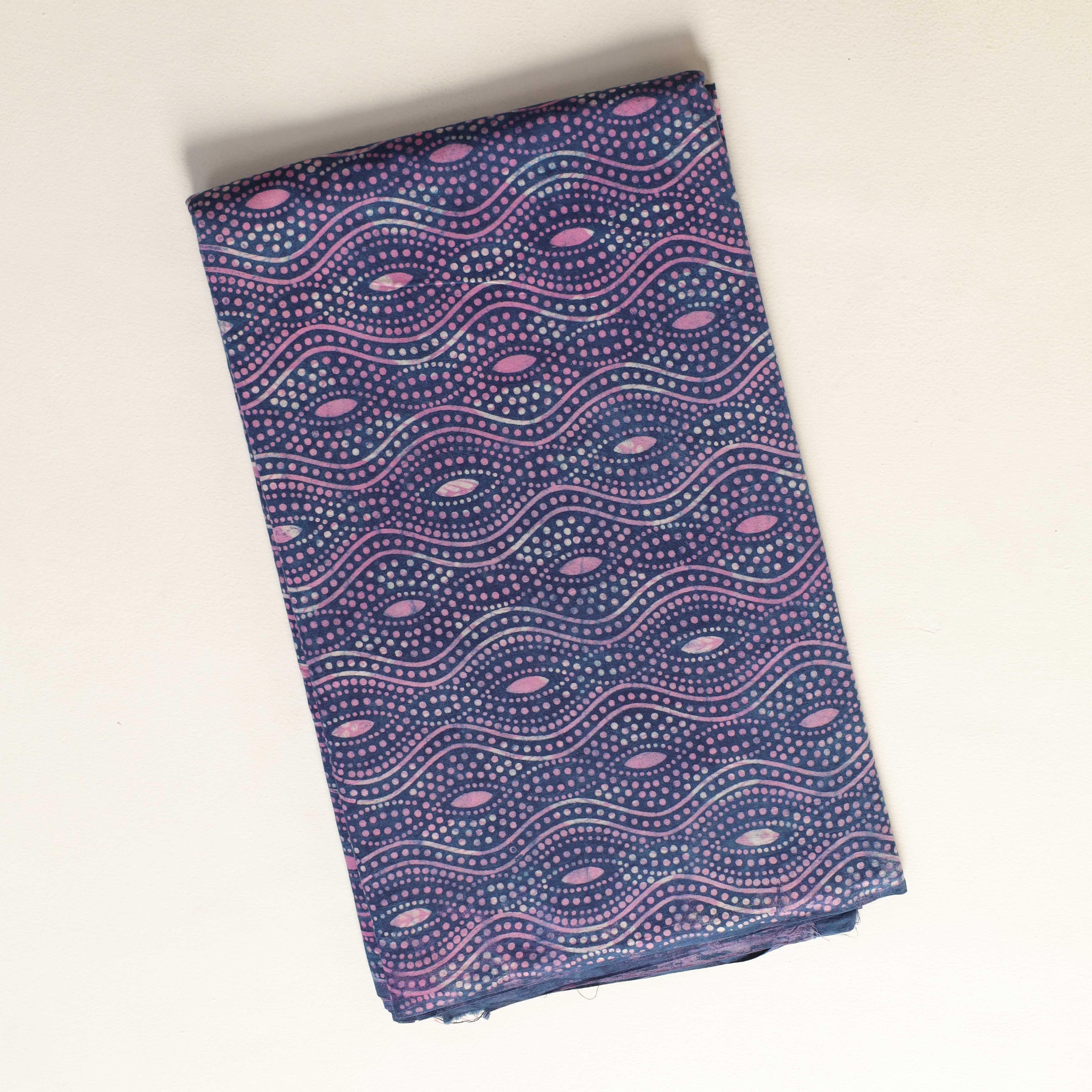 Folded fabric with a purple and pink pattern on a light beige background