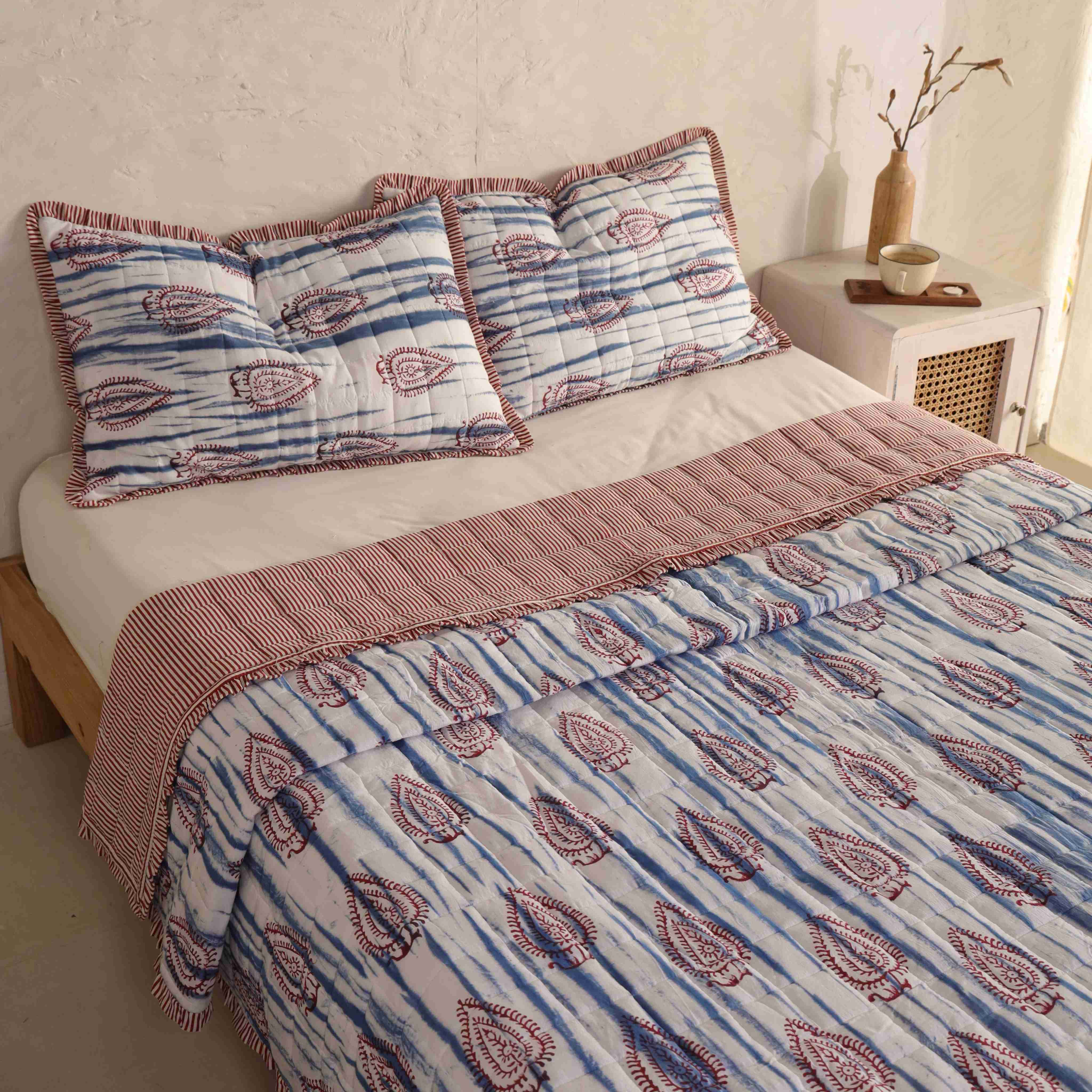 Close-up of the blue tie-dye stripes and burgundy paisley block print on the cotton quilt.