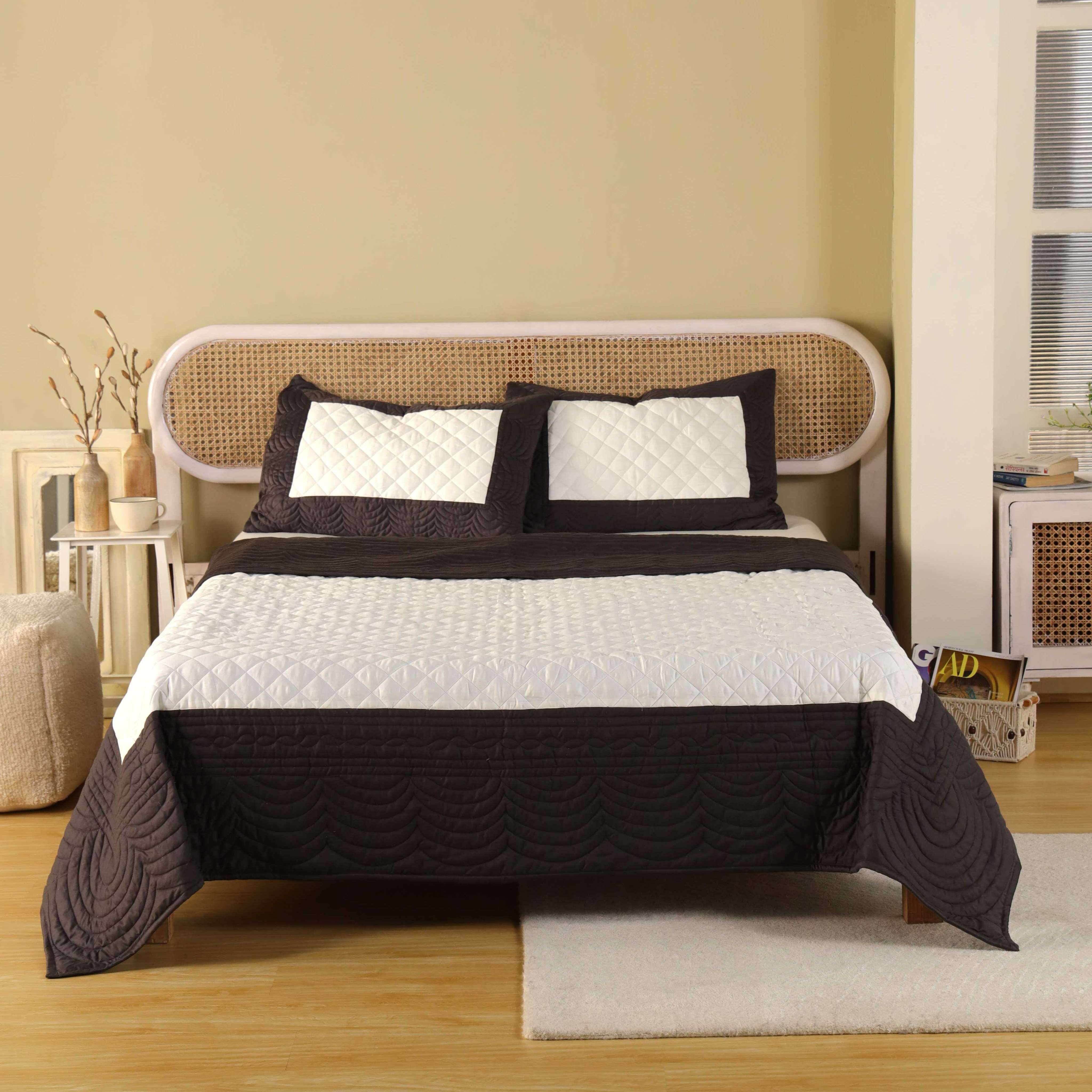 A chocolate brown and white color-block satin quilt set on a modern bed.