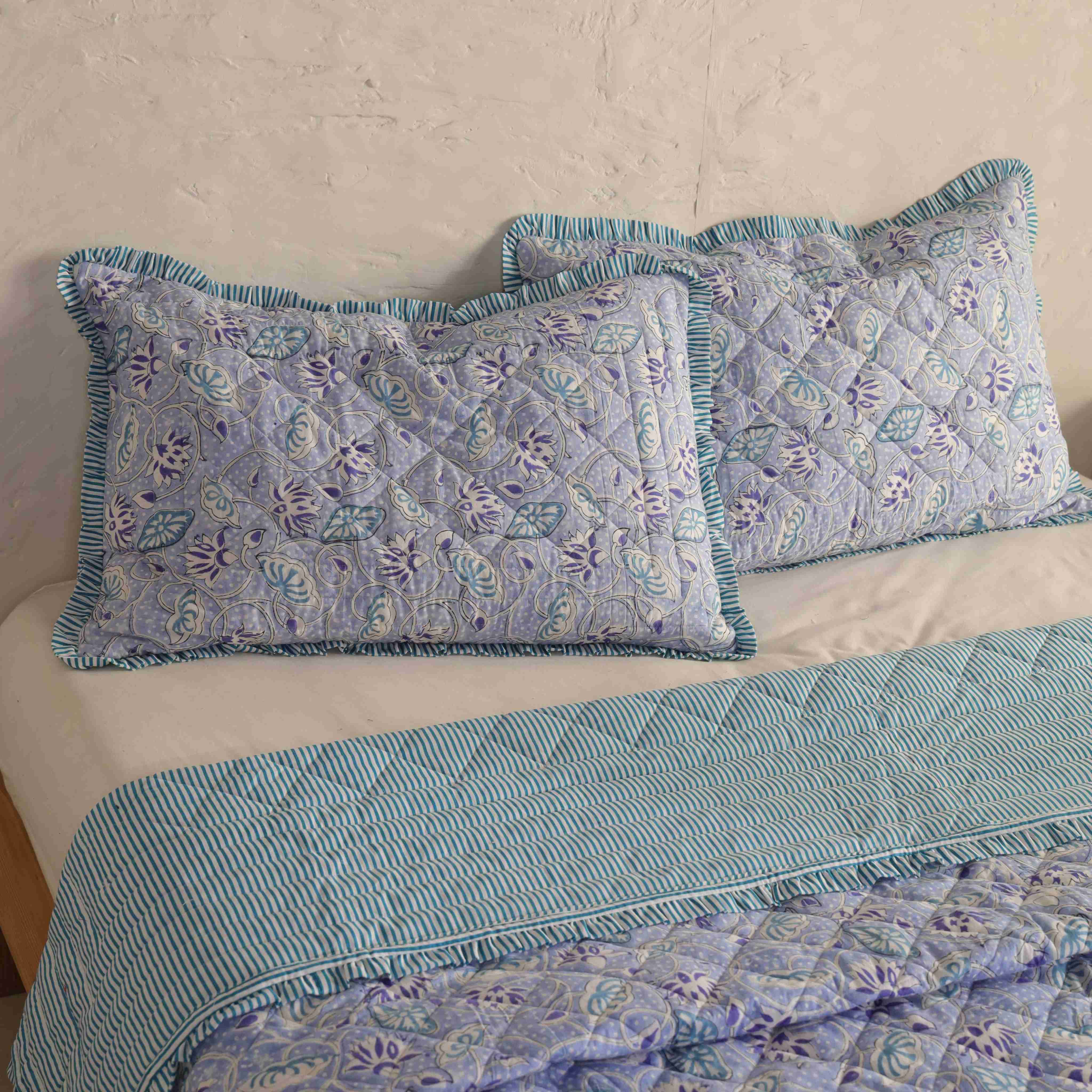 Close-up of the striped ruffle trim and blue botanical print on a cotton quilt.