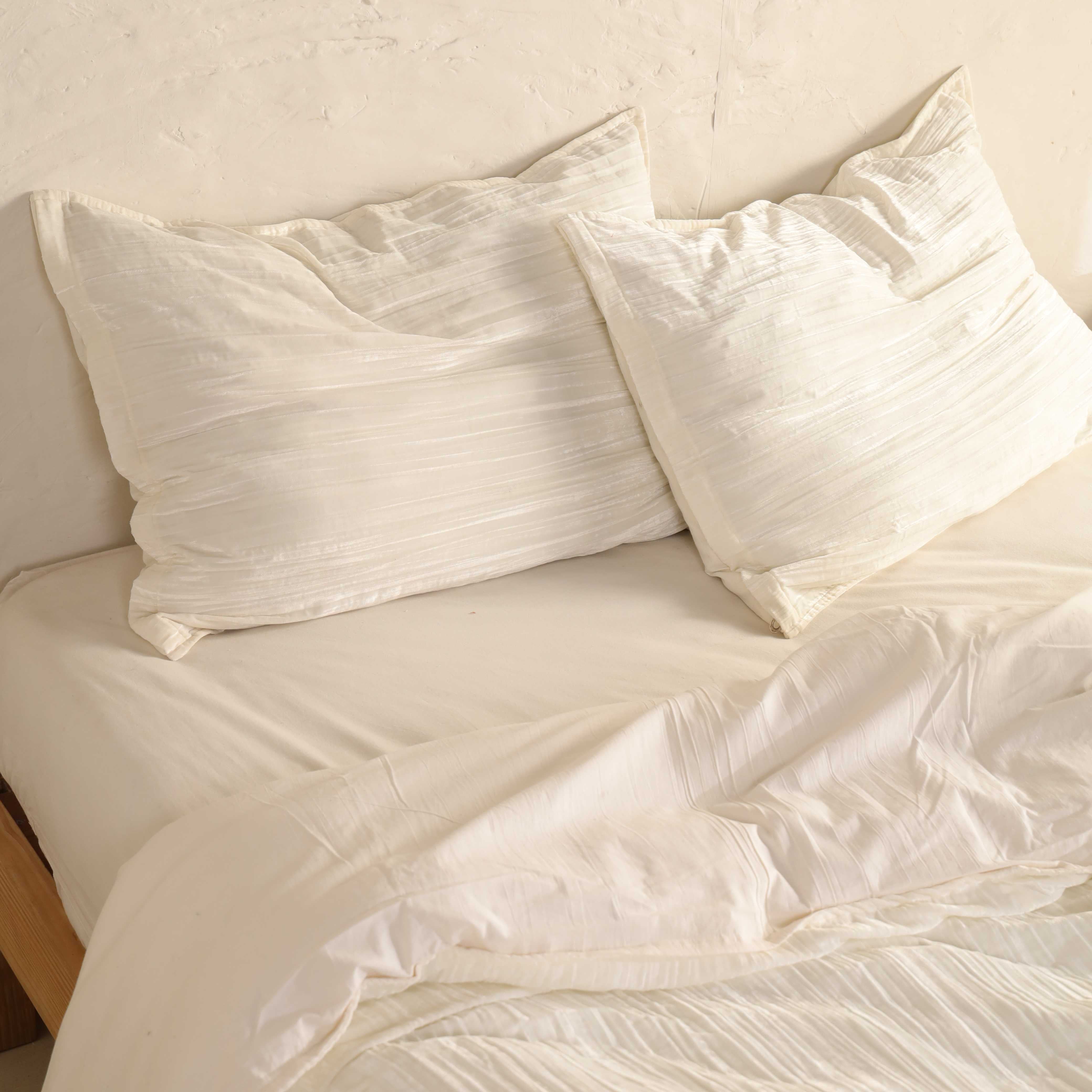 Close-up of matching velvet pillow covers showing the soft vertical pleated fabric detail.