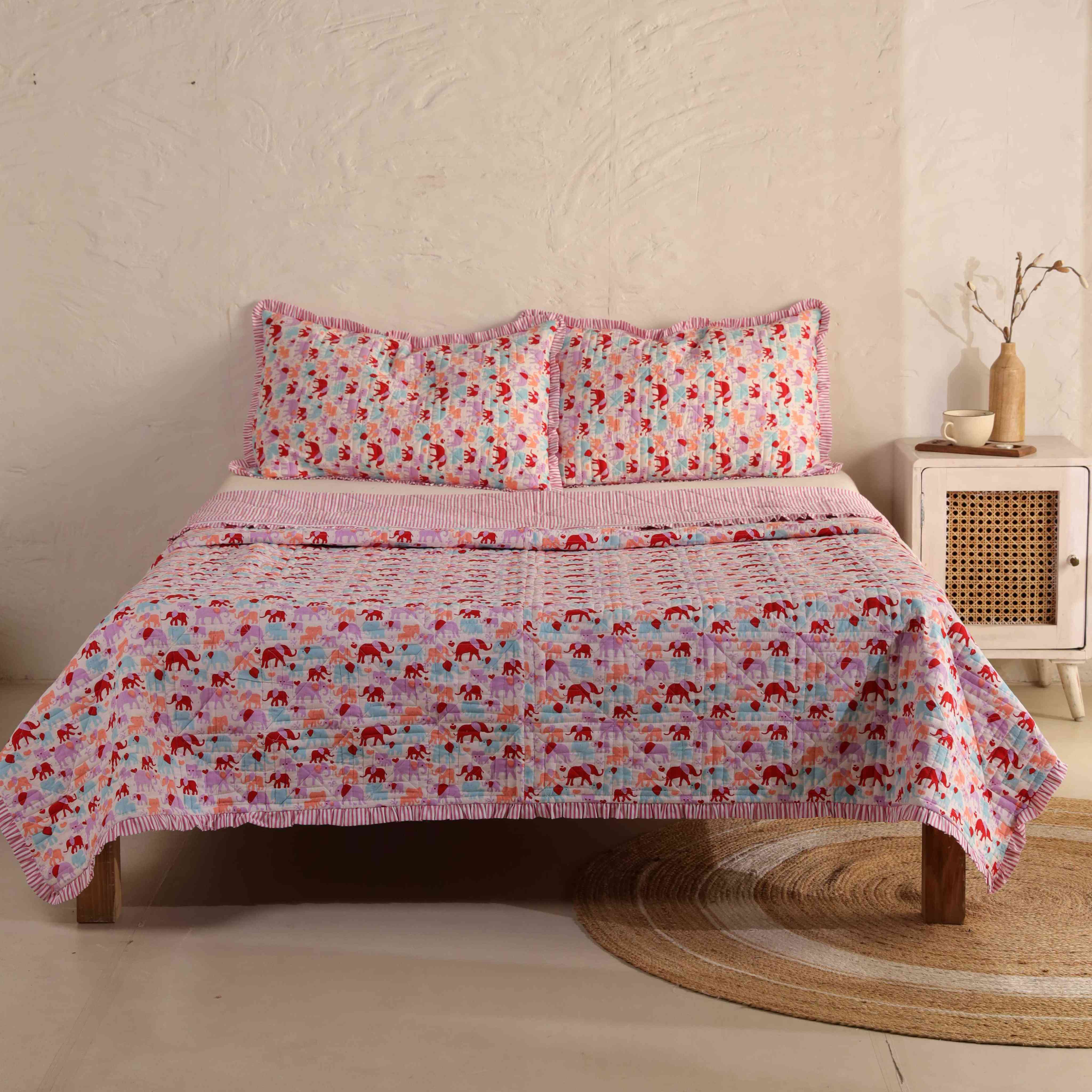 3-piece multicolor elephant print cotton quilt set with ruffled edges on a bed.