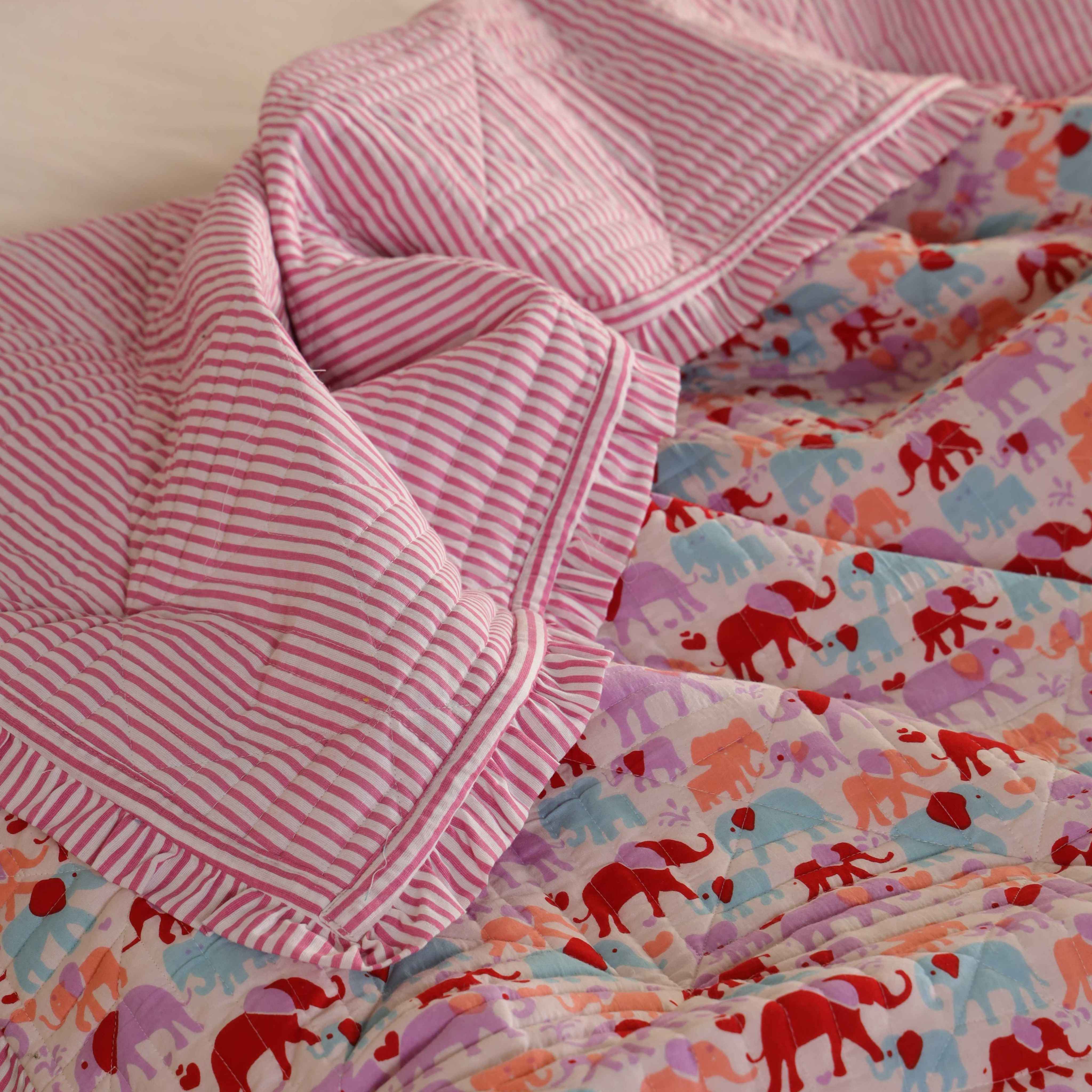 A neatly folded elephant print cotton quilt set showing the soft texture and colors.