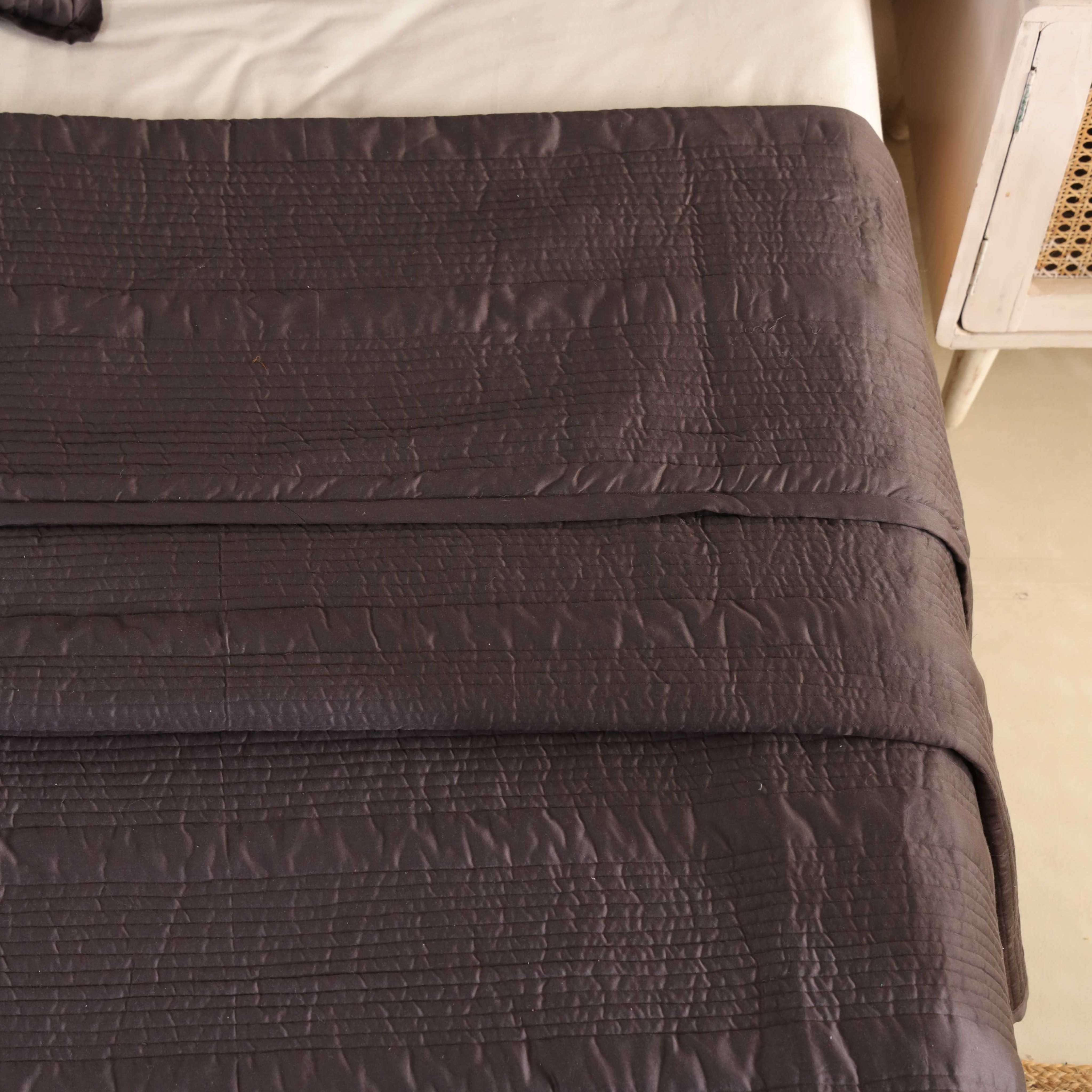A neatly folded chocolate brown velvet quilt set showing its thick, plush texture.