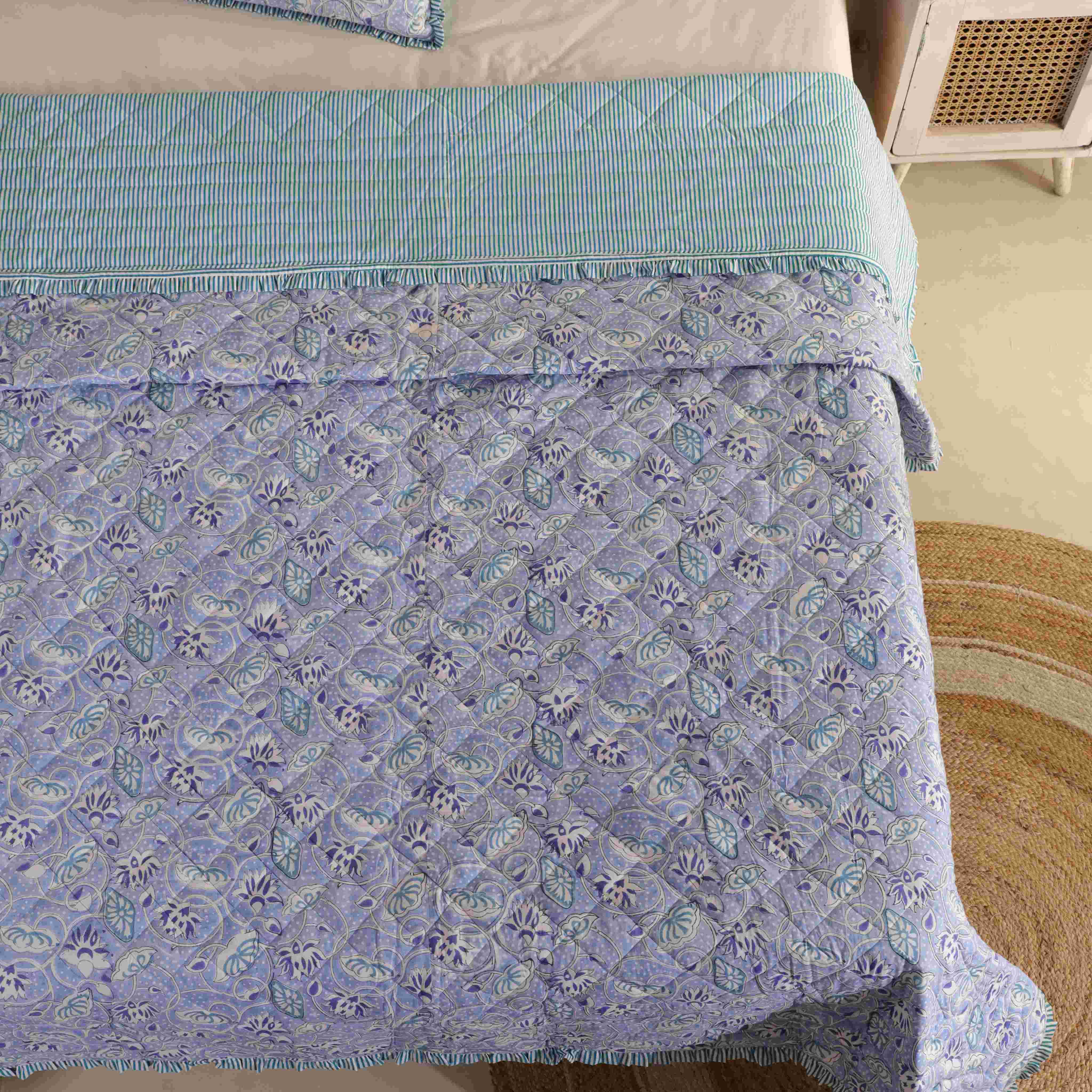 A neatly folded periwinkle floral cotton quilt set showing the soft texture.
