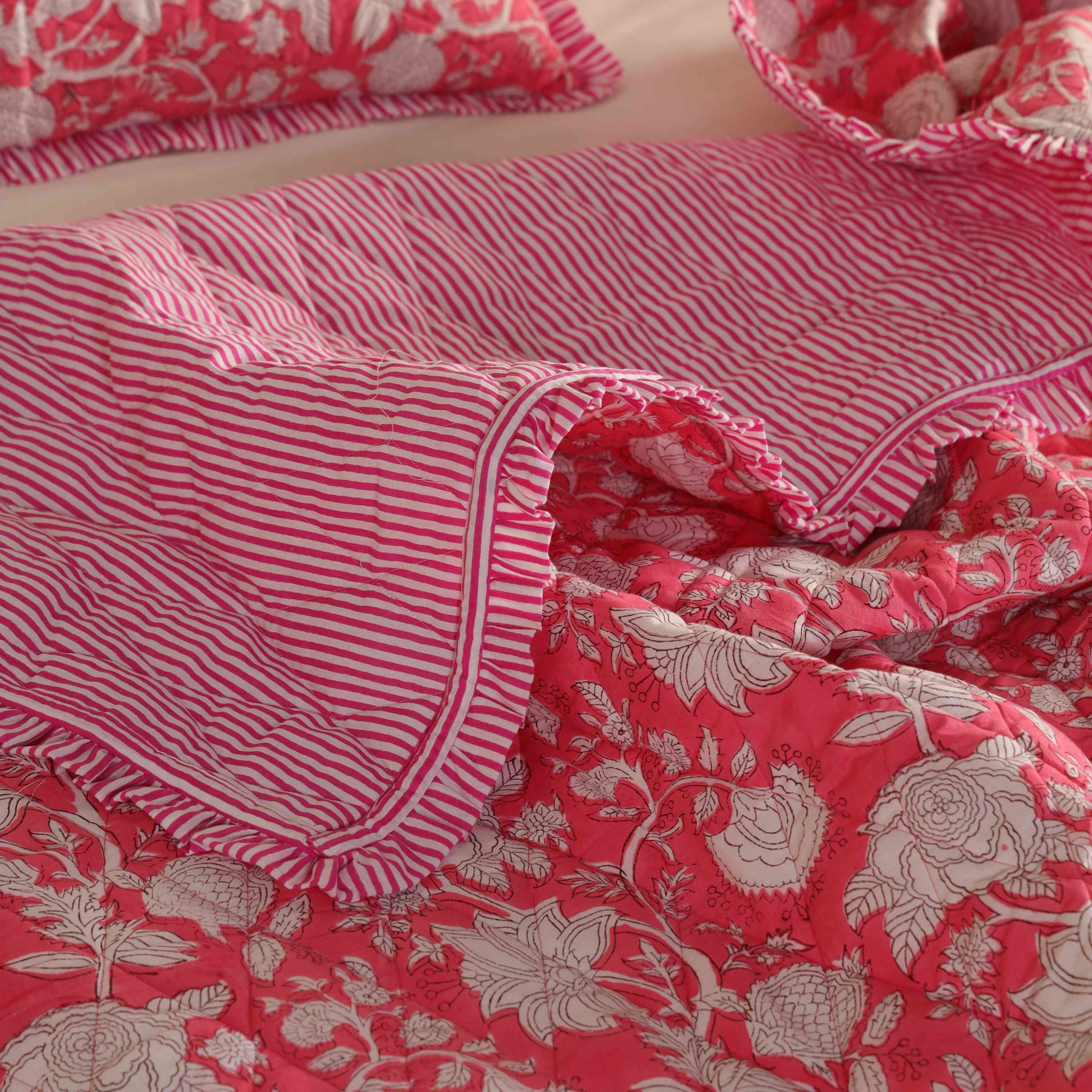 A neatly folded rose pink floral quilt set showing the soft cotton texture.