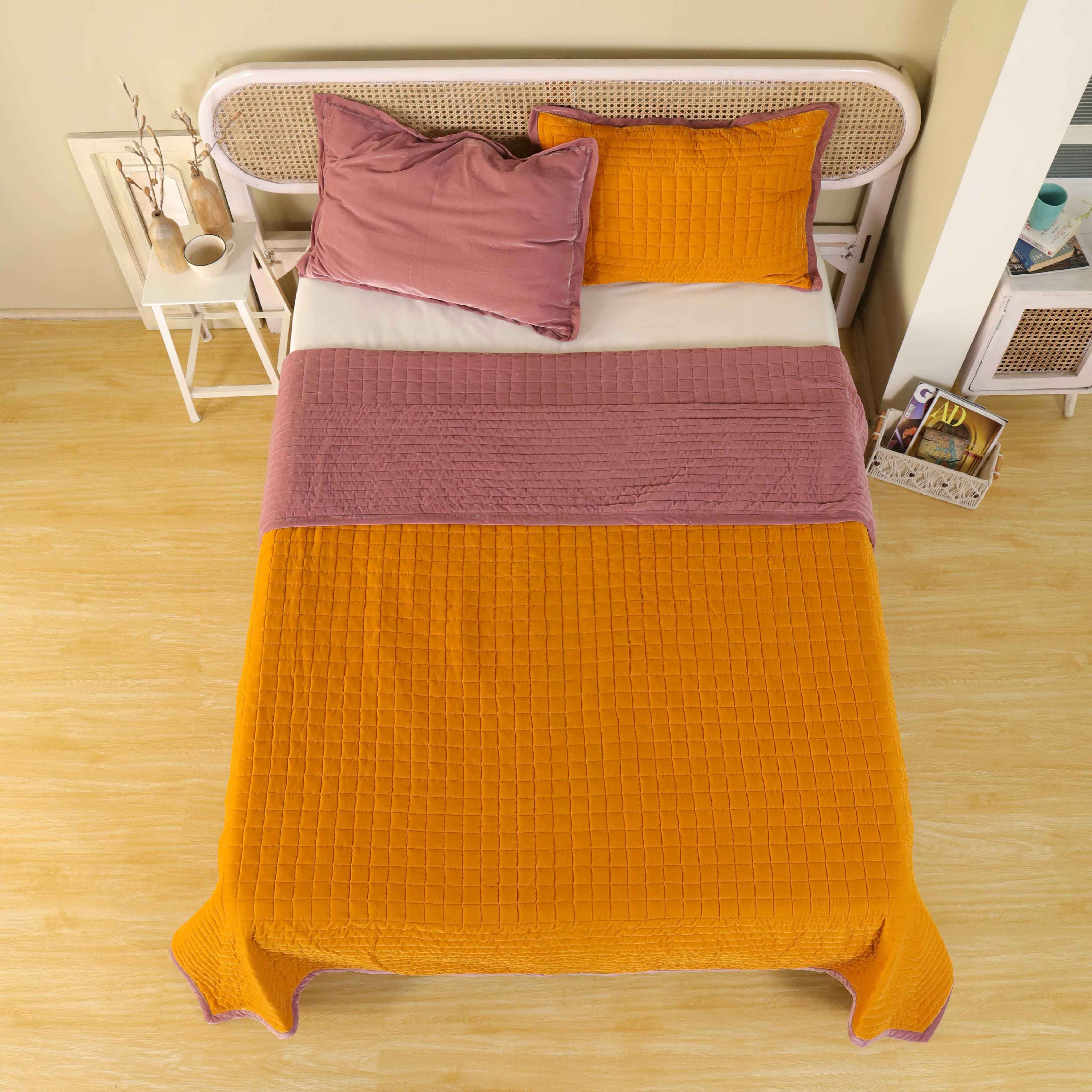 High-angle lifestyle shot of a cozy bedroom featuring a reversible yellow and pink velvet duvet set.