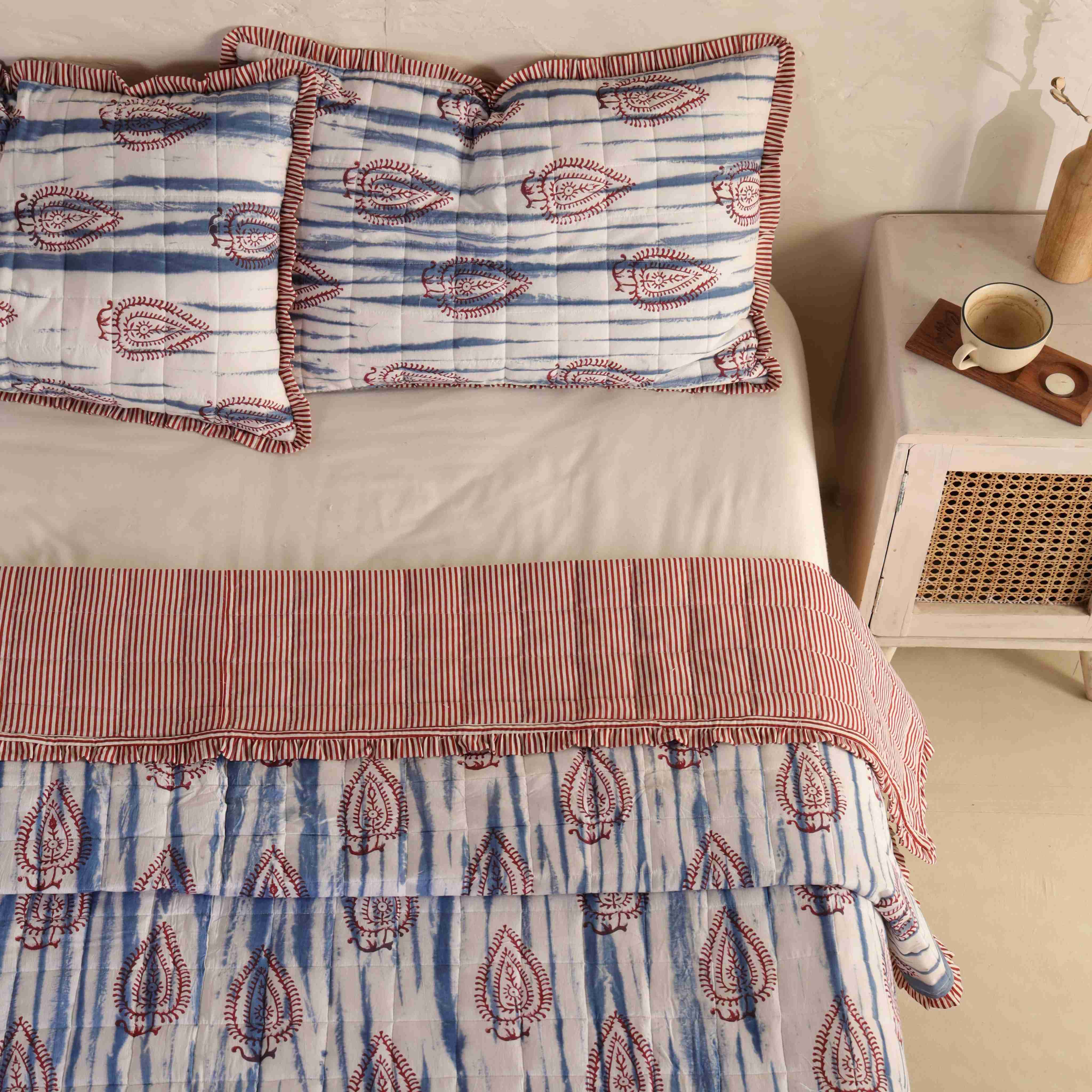 Eclectic boho bedroom interior featuring a blue and white block print cotton quilt.