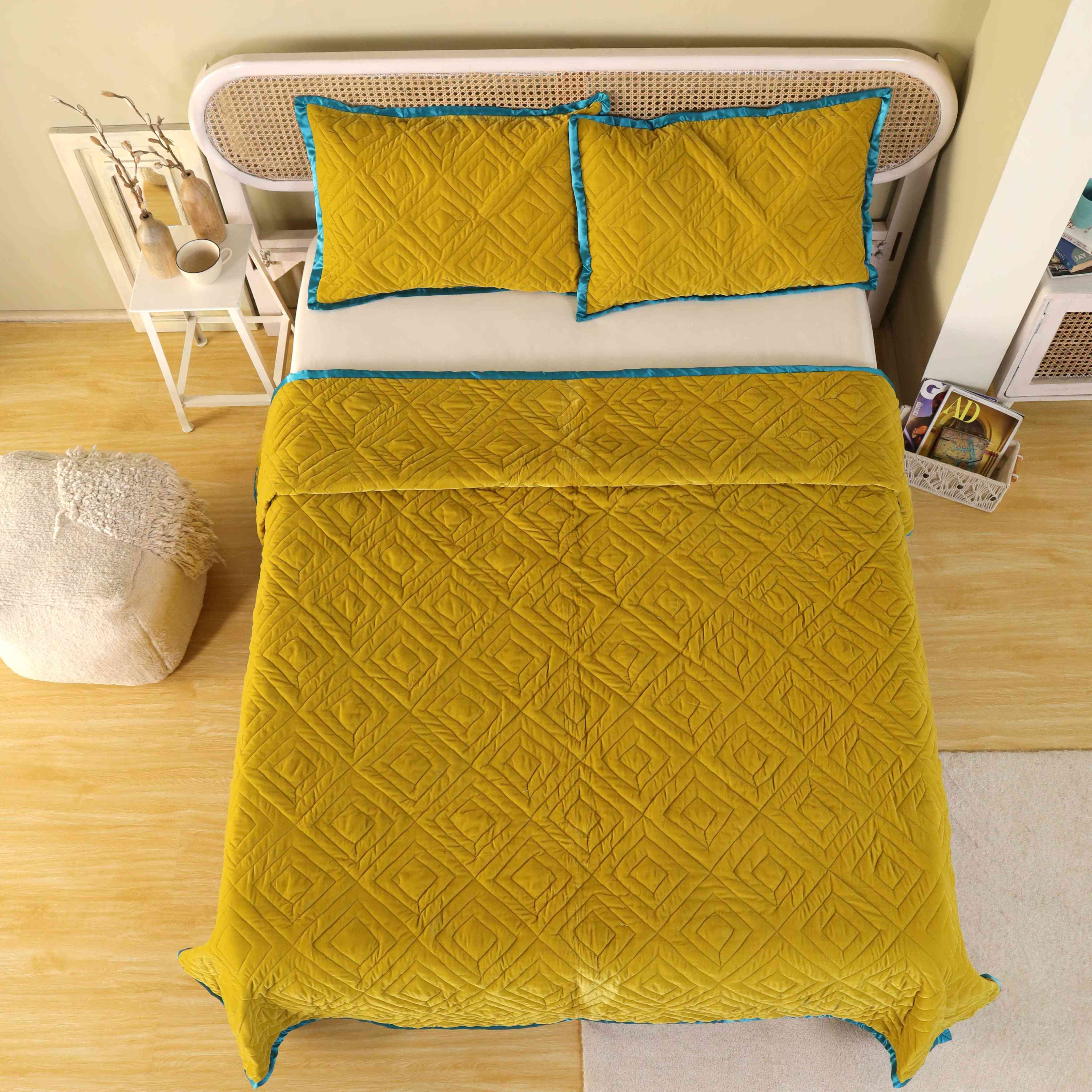 Modern bedroom styling featuring a yellow satin quilt set and a white cane headboard.