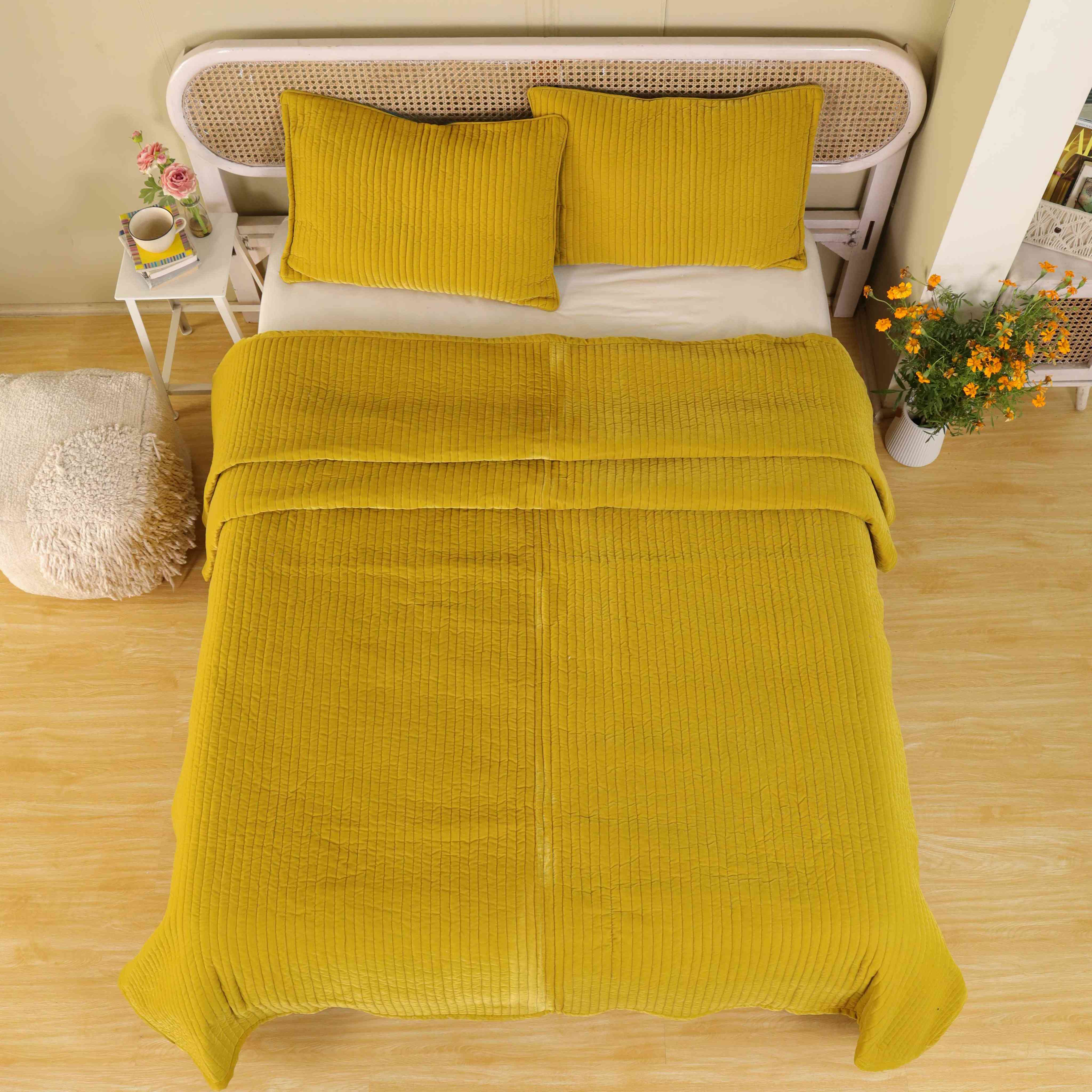 Lifestyle shot of a cozy boho bedroom styled with a mustard yellow velvet duvet and floral accents.